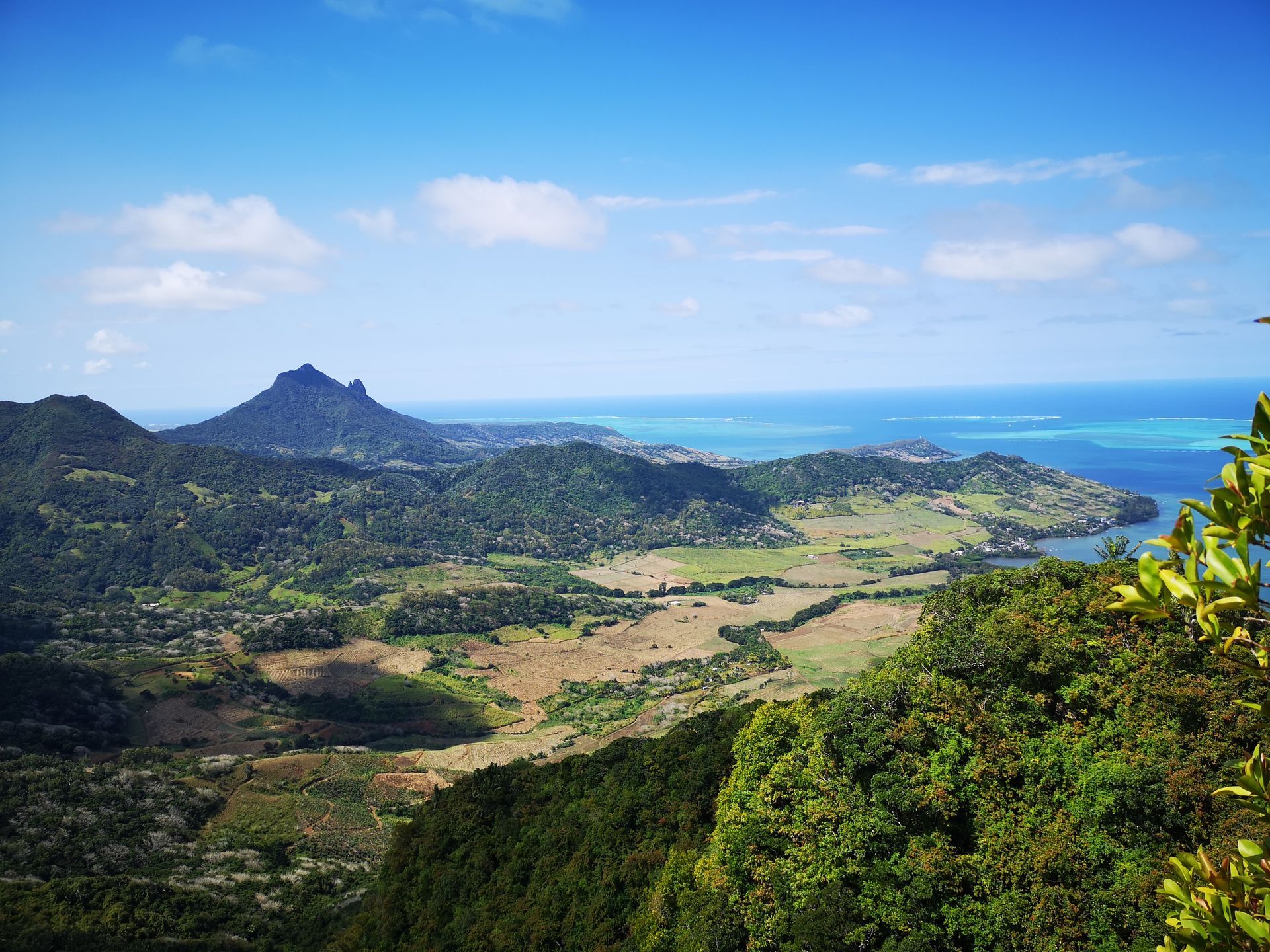 A view of a lush green valley with mountains in the background and the ocean in the foreground on the East Coast of Mauritius