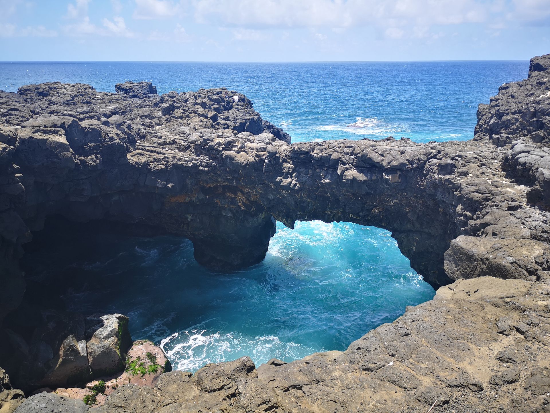 A large rock formation overlooking the ocean with waves crashing against it on the South Coast of Mauritius