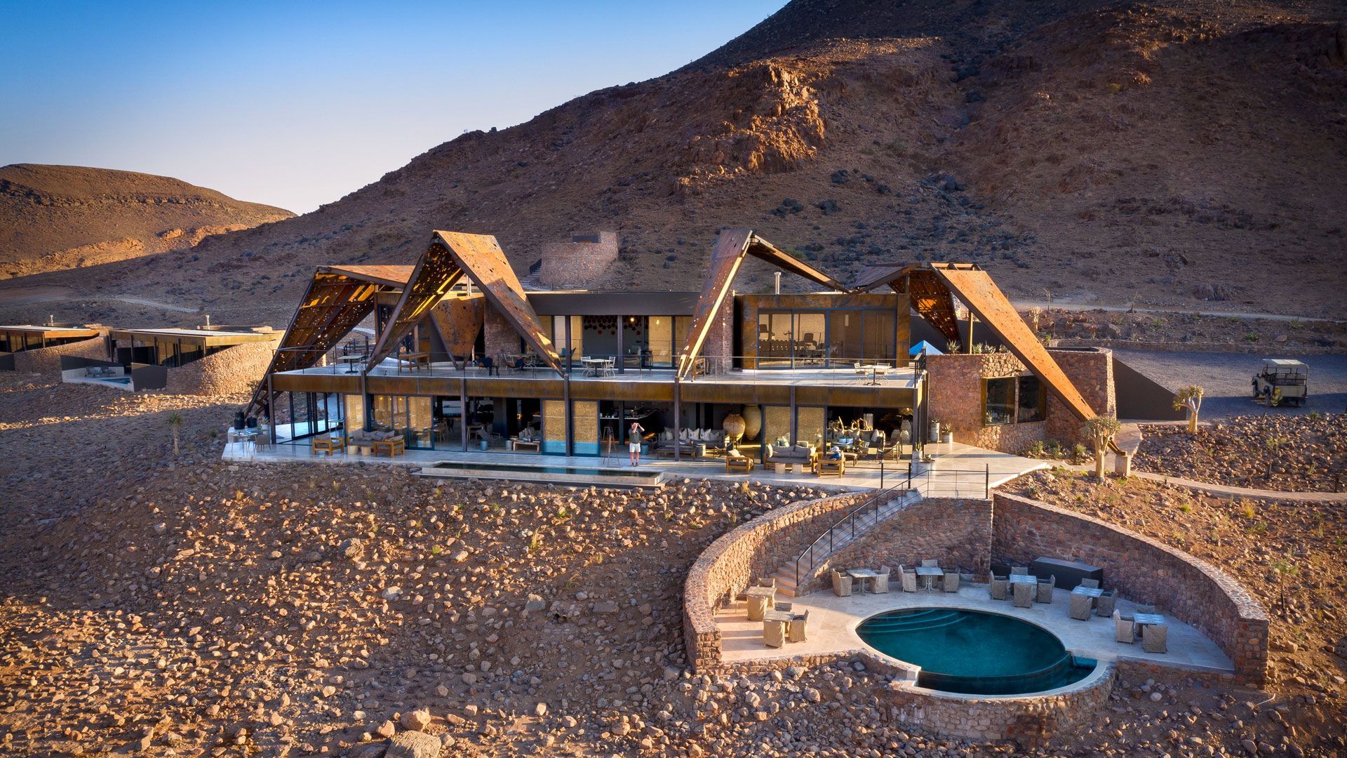 A large house with a pool in the middle of the desert at andBeyond Sossusvlei Desert Lodge