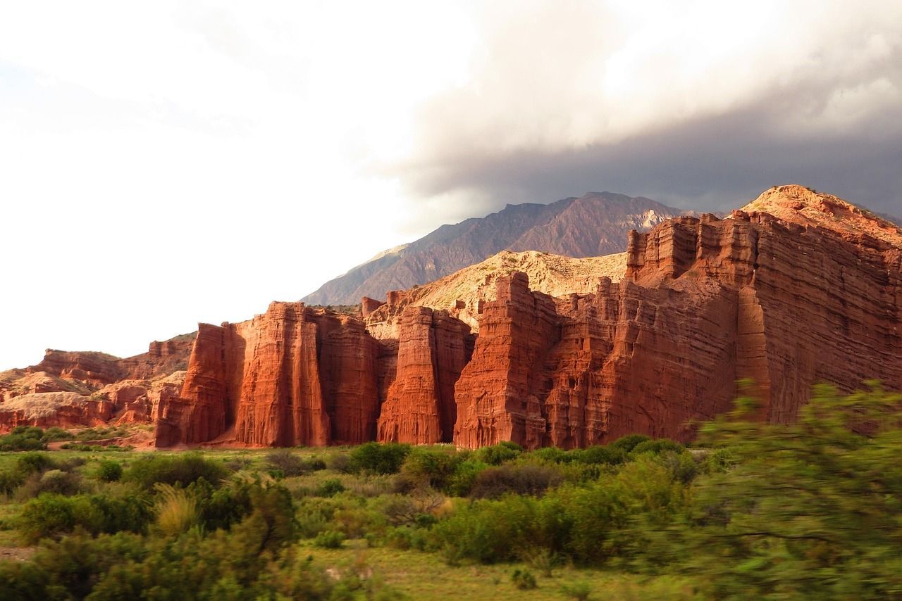 A large rock formation in the middle of a field with a mountain in the background.