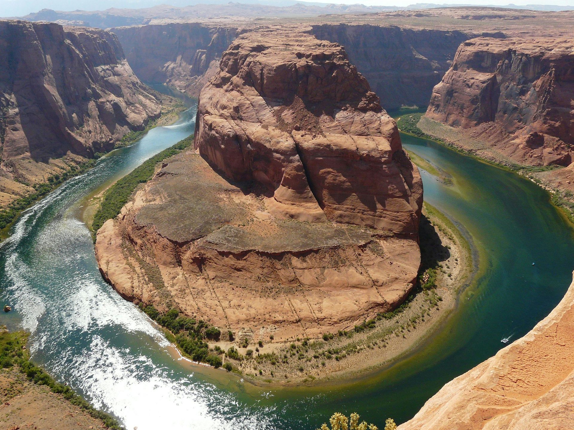 The Colorado river flowing through a canyon with a large rock in the middle.