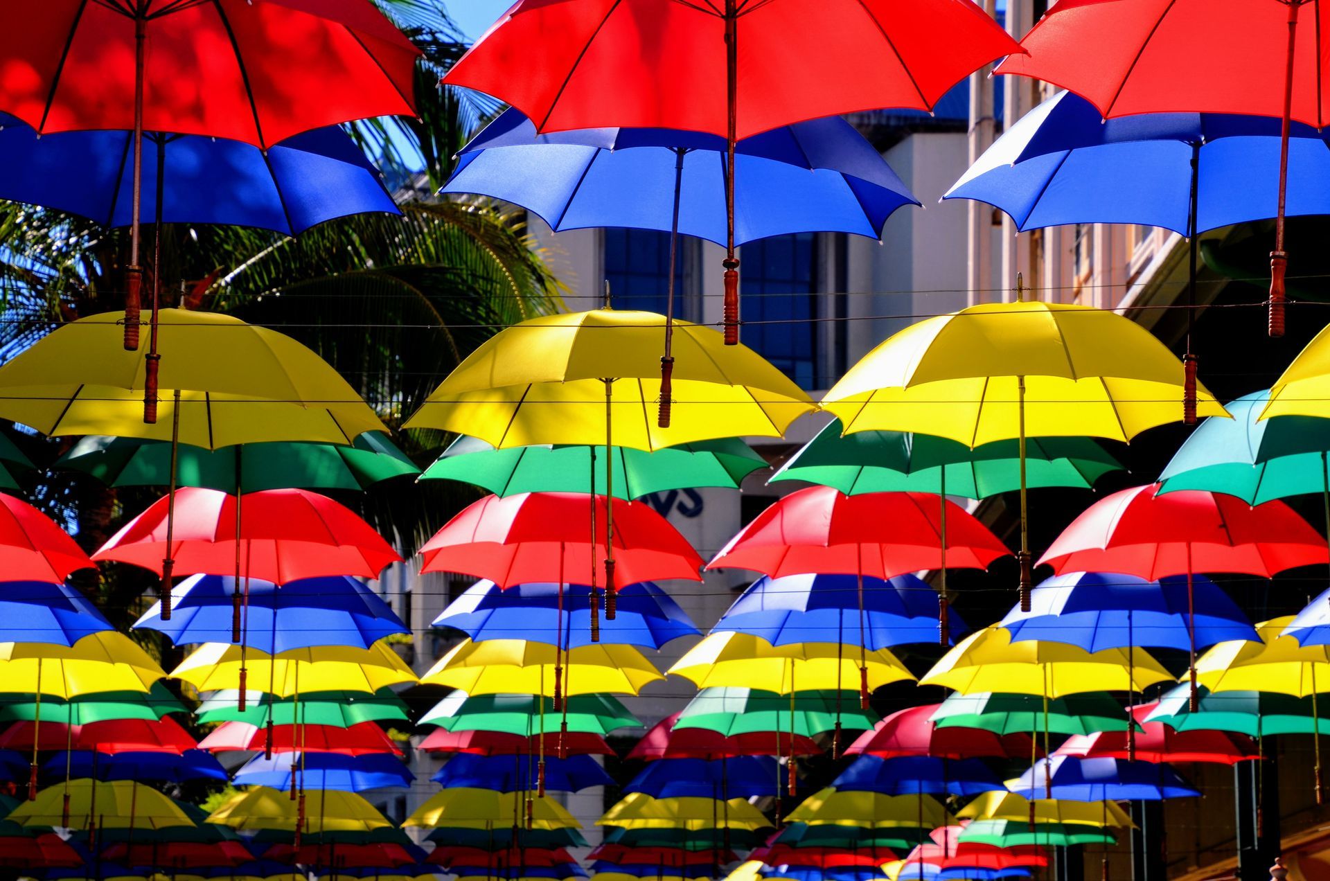 A bunch of umbrellas  resembling the colours of Mauritian Flag are hanging from a pole on a street in Port Louis, Mauritius.