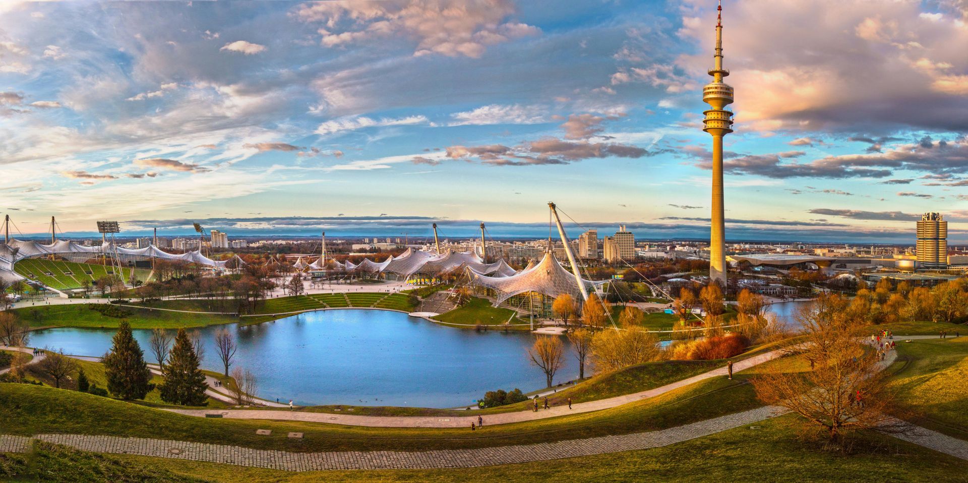 A panoramic view of a  Bavarian city with a lake and a tower.