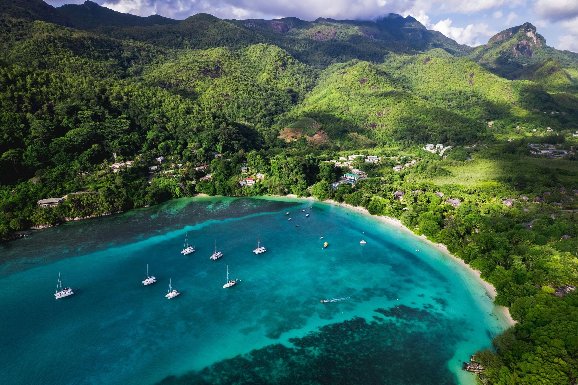 An aerial view of a bay with boats in it and mountains in the background.