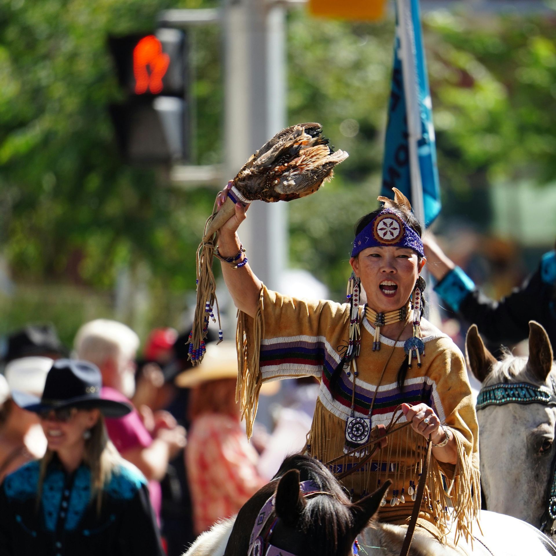 A woman in a native american outfit is riding a horse in Calgary