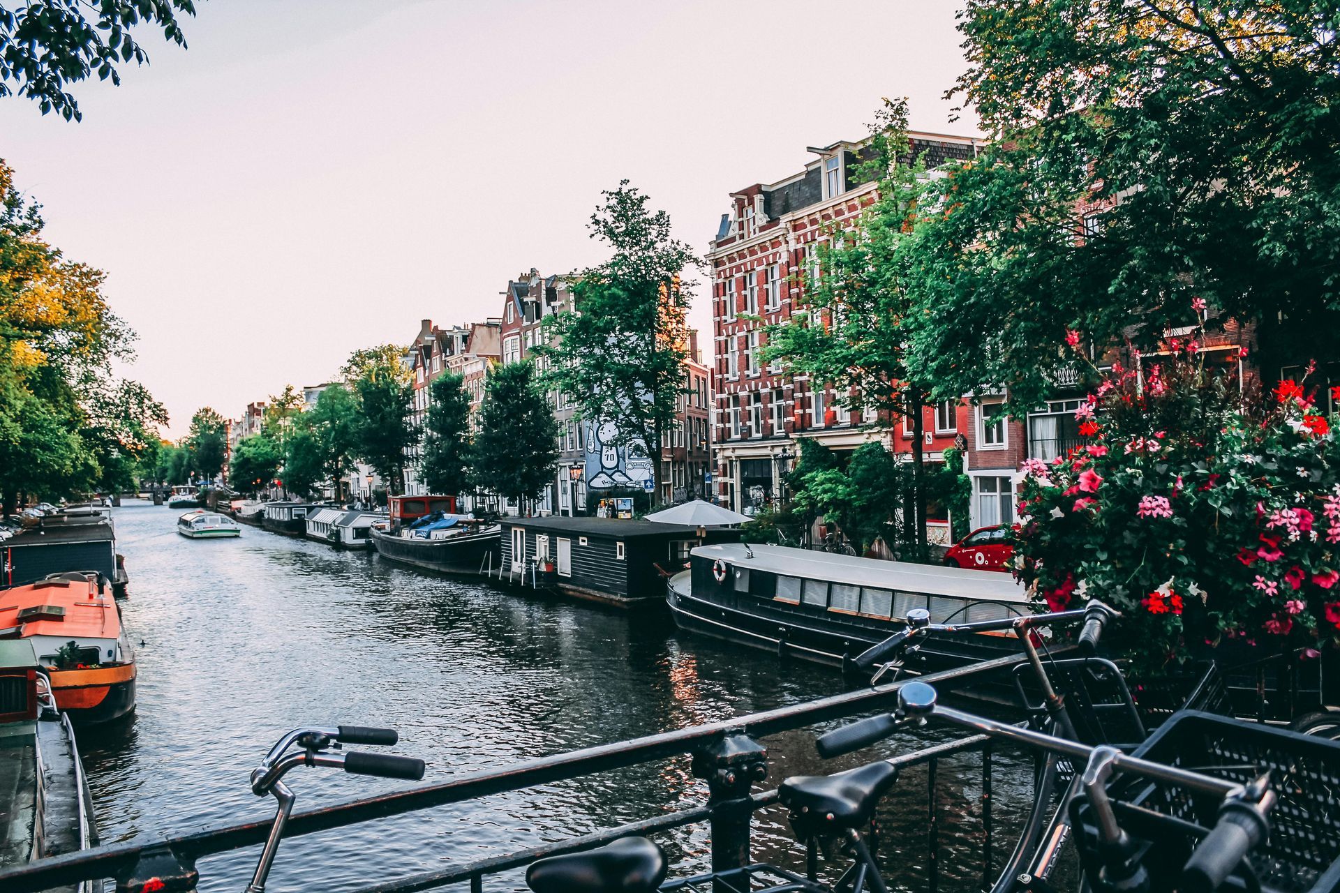 A row of bicycles are parked on a bridge over a river.