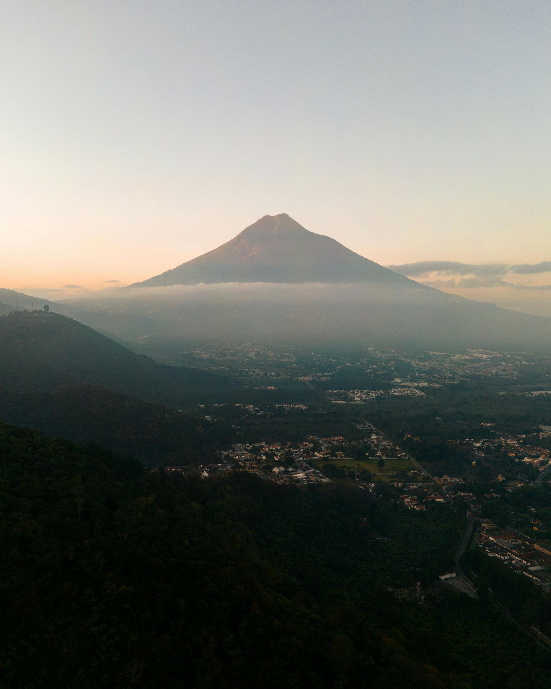 A mountain with a city in the foreground and a city in the background