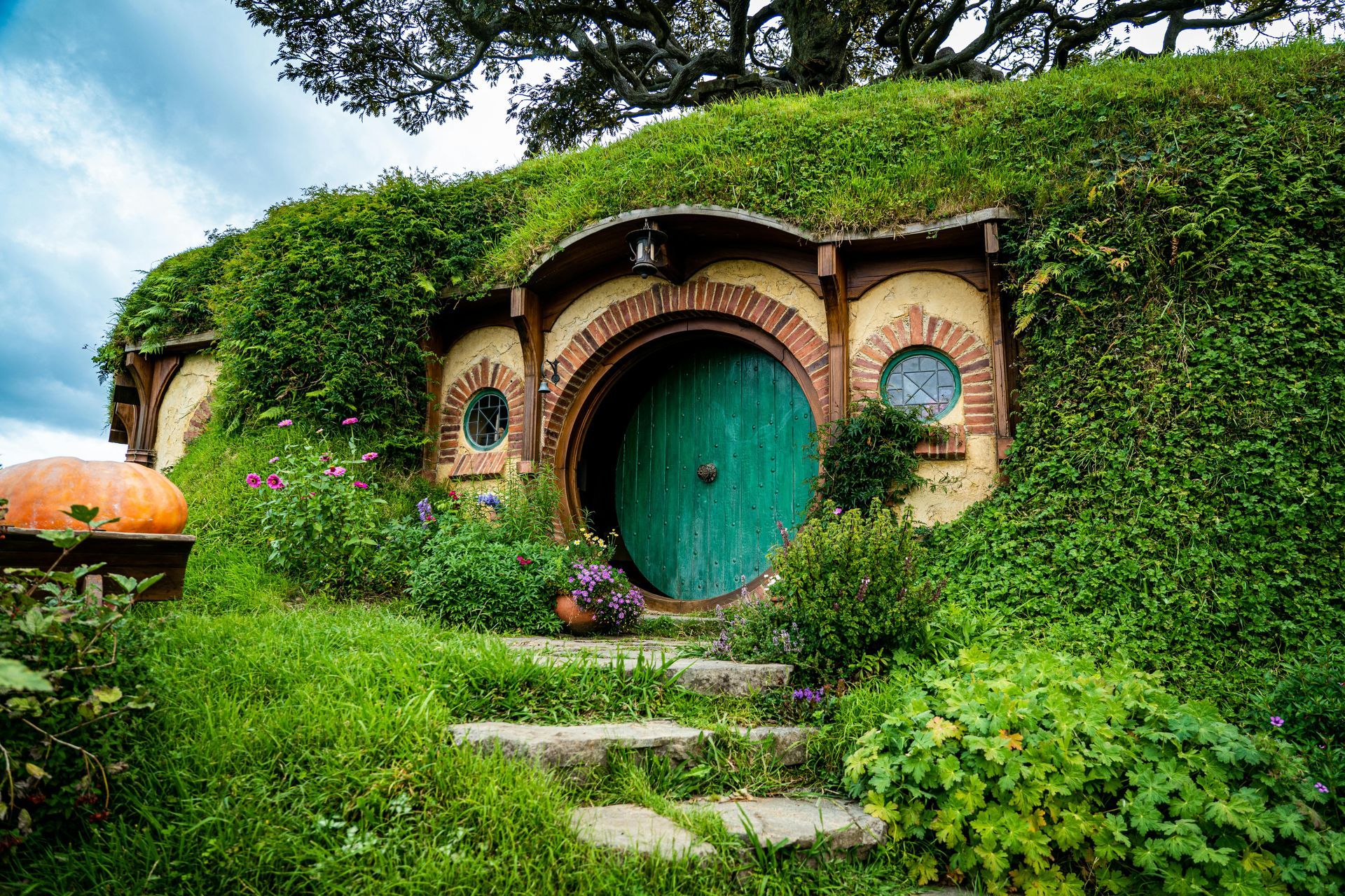 A small house with a green door is sitting on top of a hill. The film set from the Hobbit.
