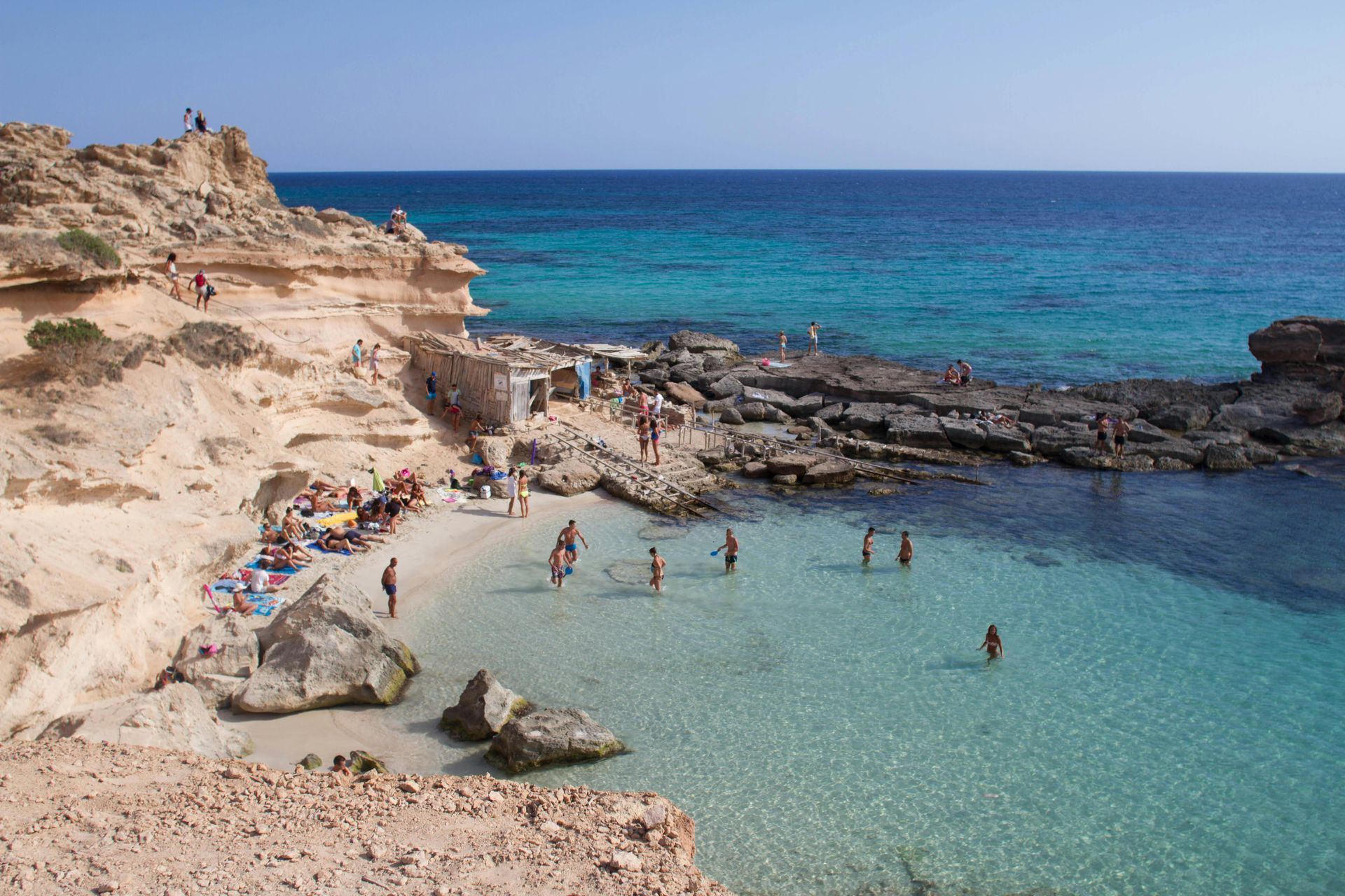 A group of people are swimming in the ocean on a beach in Ibizia