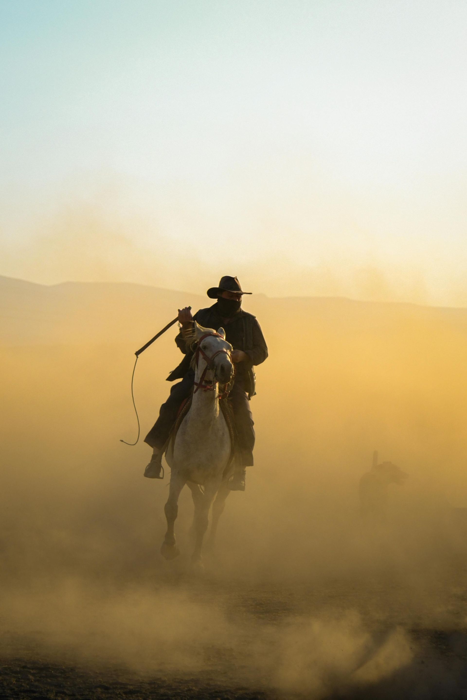 A man is riding a horse in the desert at sunset in the Wild West