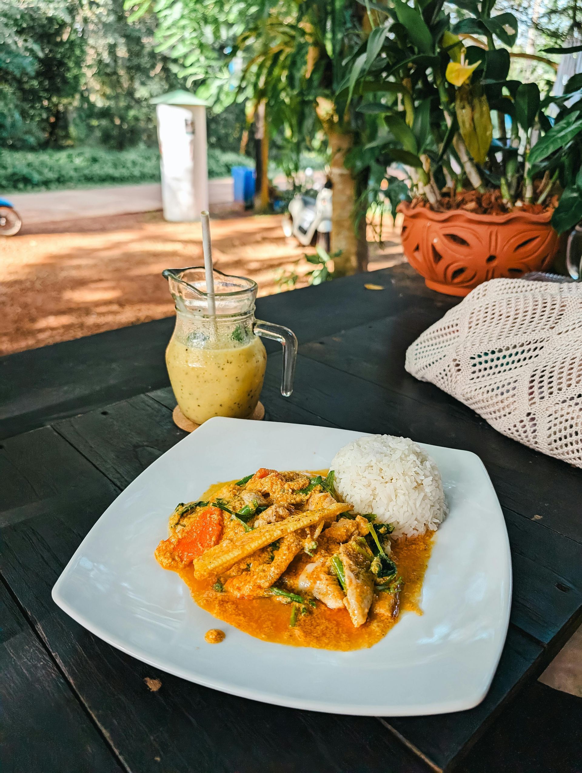 A plate of food with thai rice and a drink on a table.