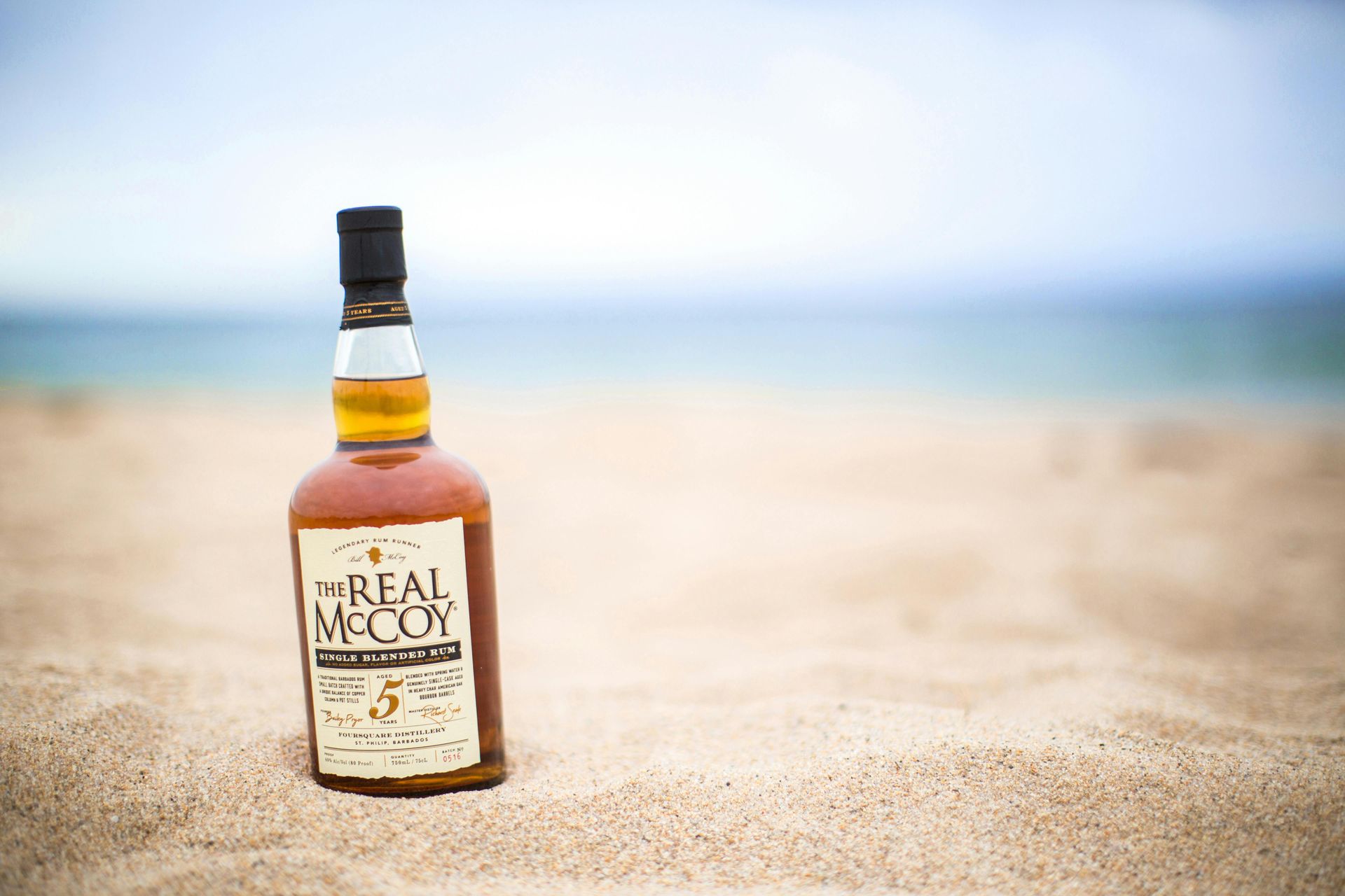A bottle of Real McCoy Rum on the beach.