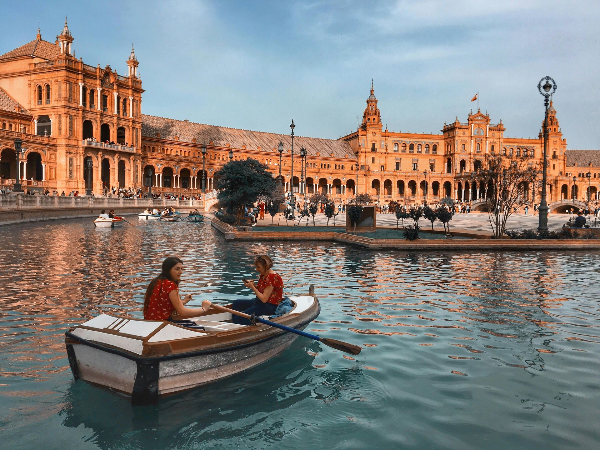 Two people are rowing a boat on a lake in front of a building.