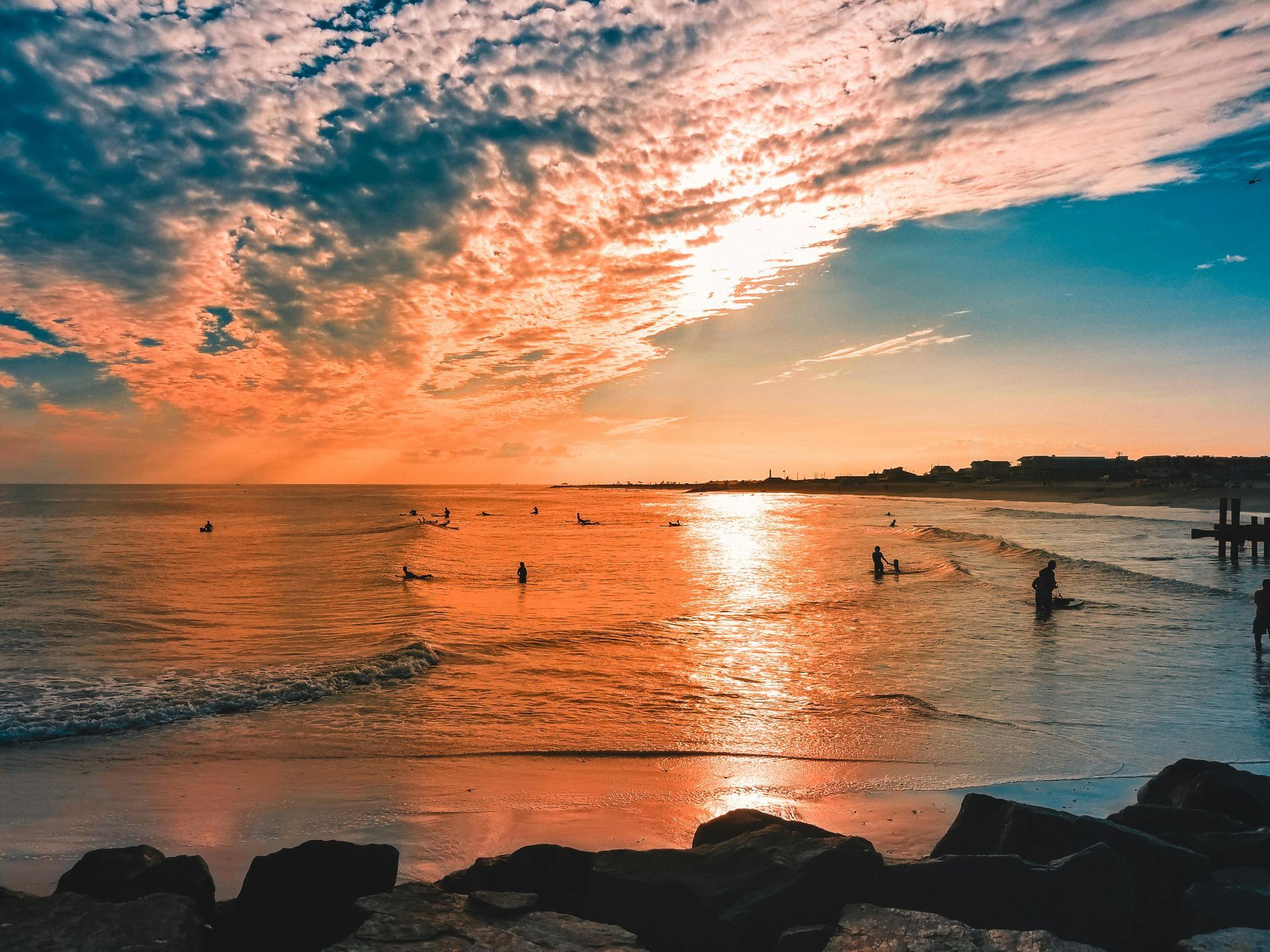 A group of people are swimming in the ocean at sunset in New Jersey