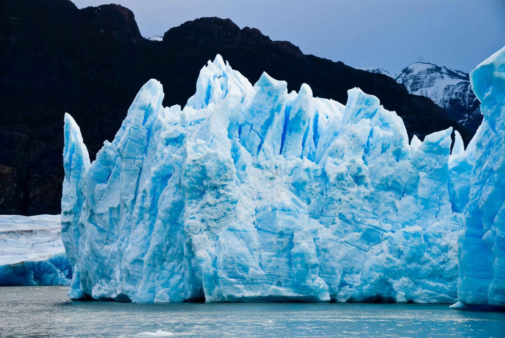 A large iceberg is floating in the water with mountains in the background in El Calafate