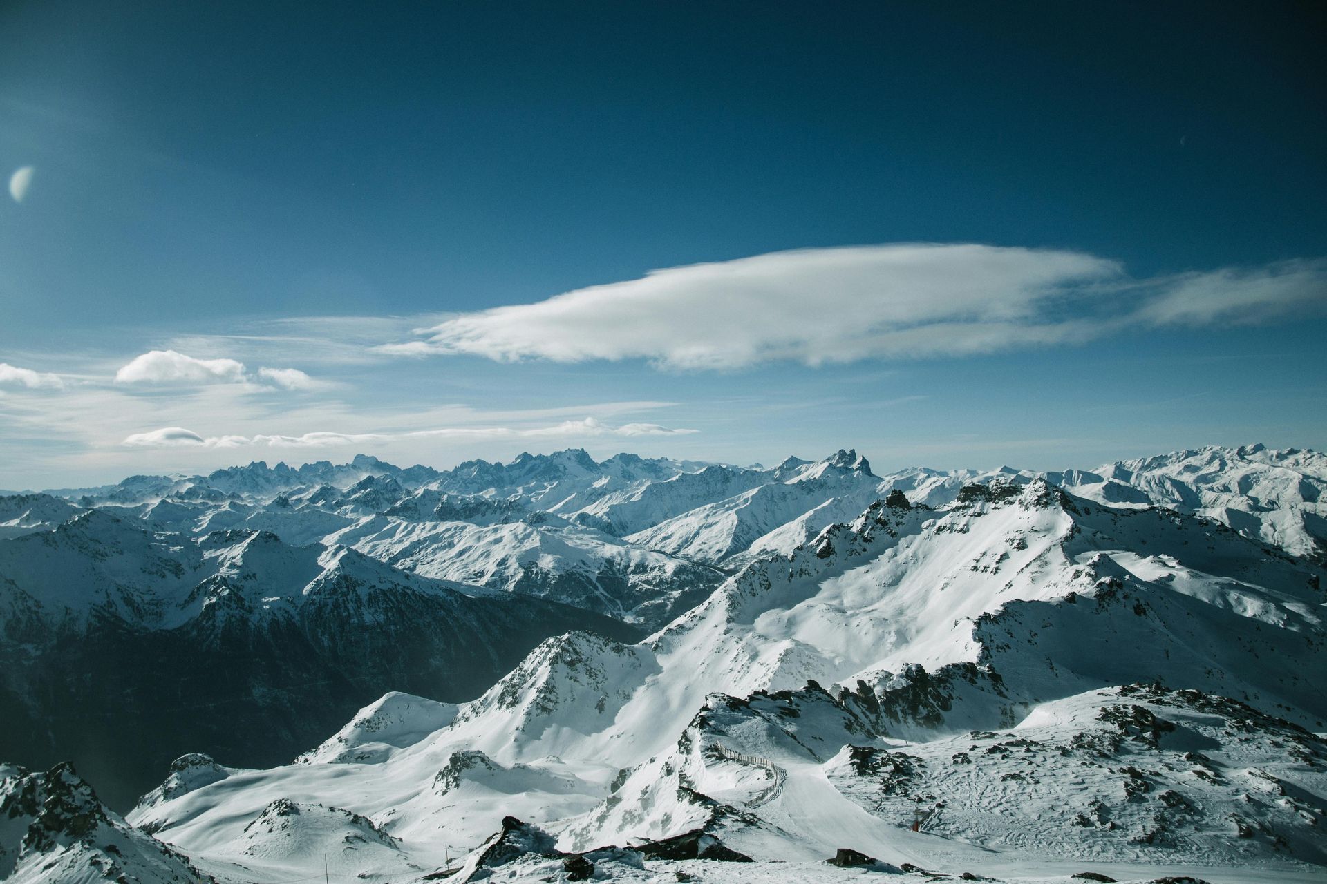 A snowy mountain range with a cloud in the sky of the French Alps