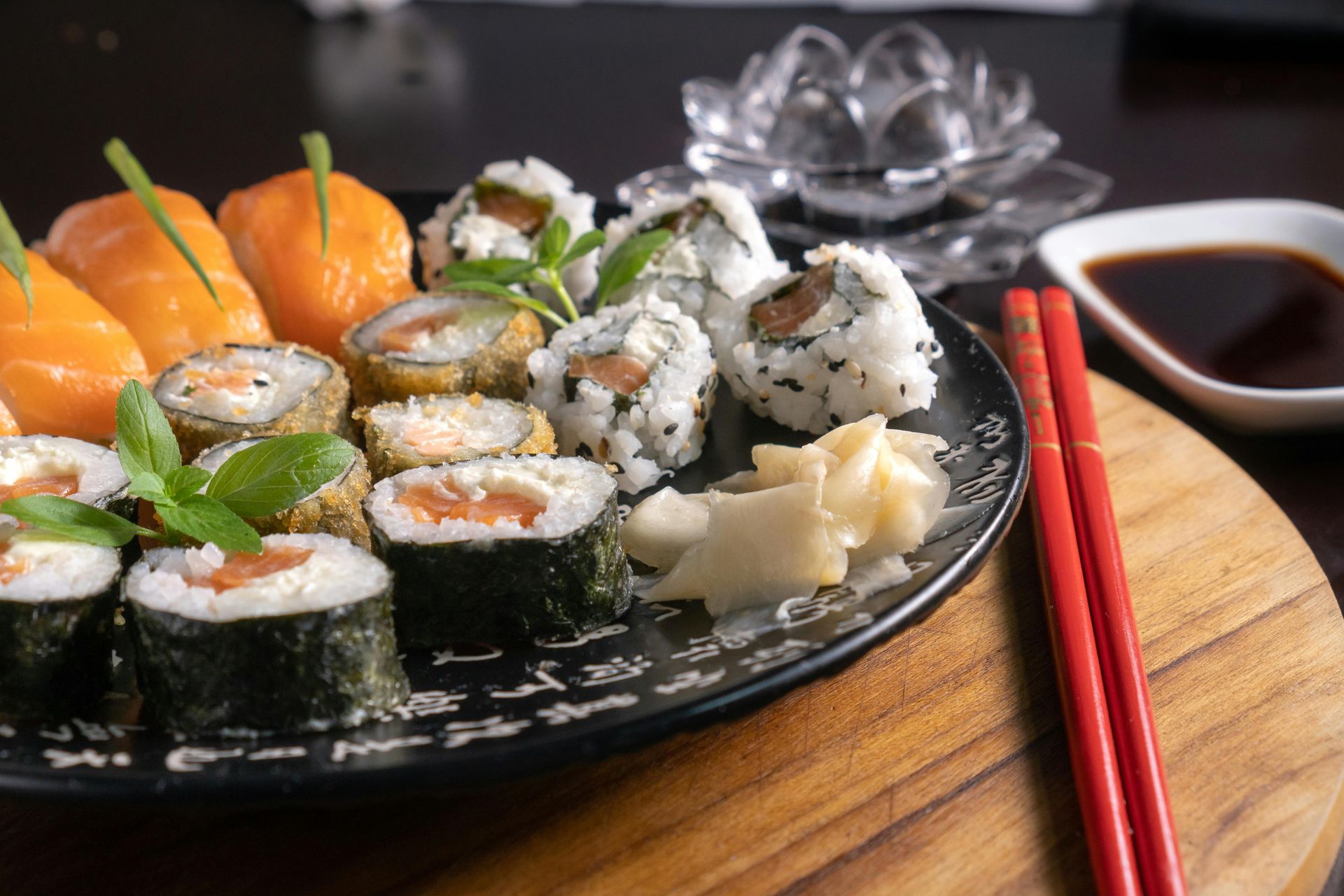 A plate of sushi and chopsticks on a wooden table.