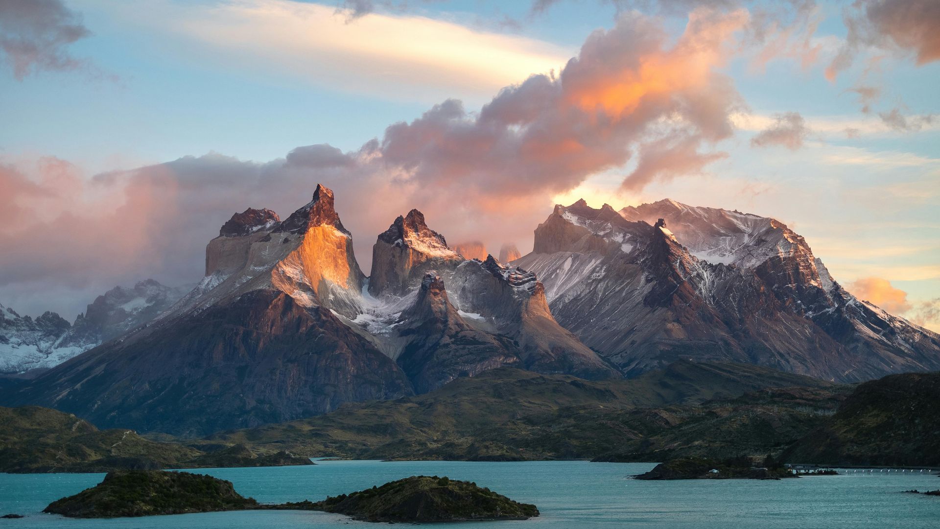 The Andes mountain range with a lake in the foreground and a cloudy sky in the background in Chile