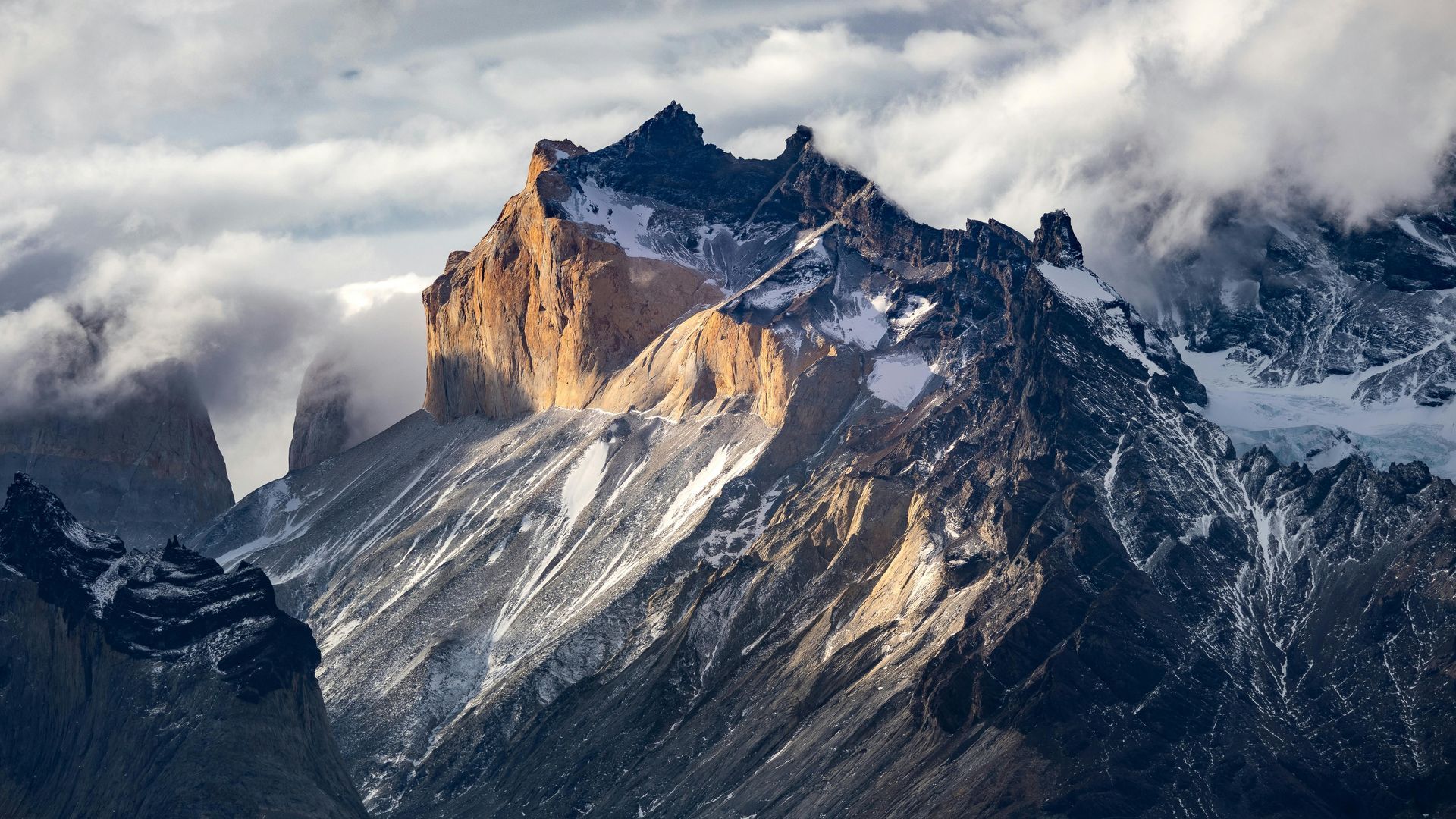 A mountain covered in snow and clouds on a cloudy day.
