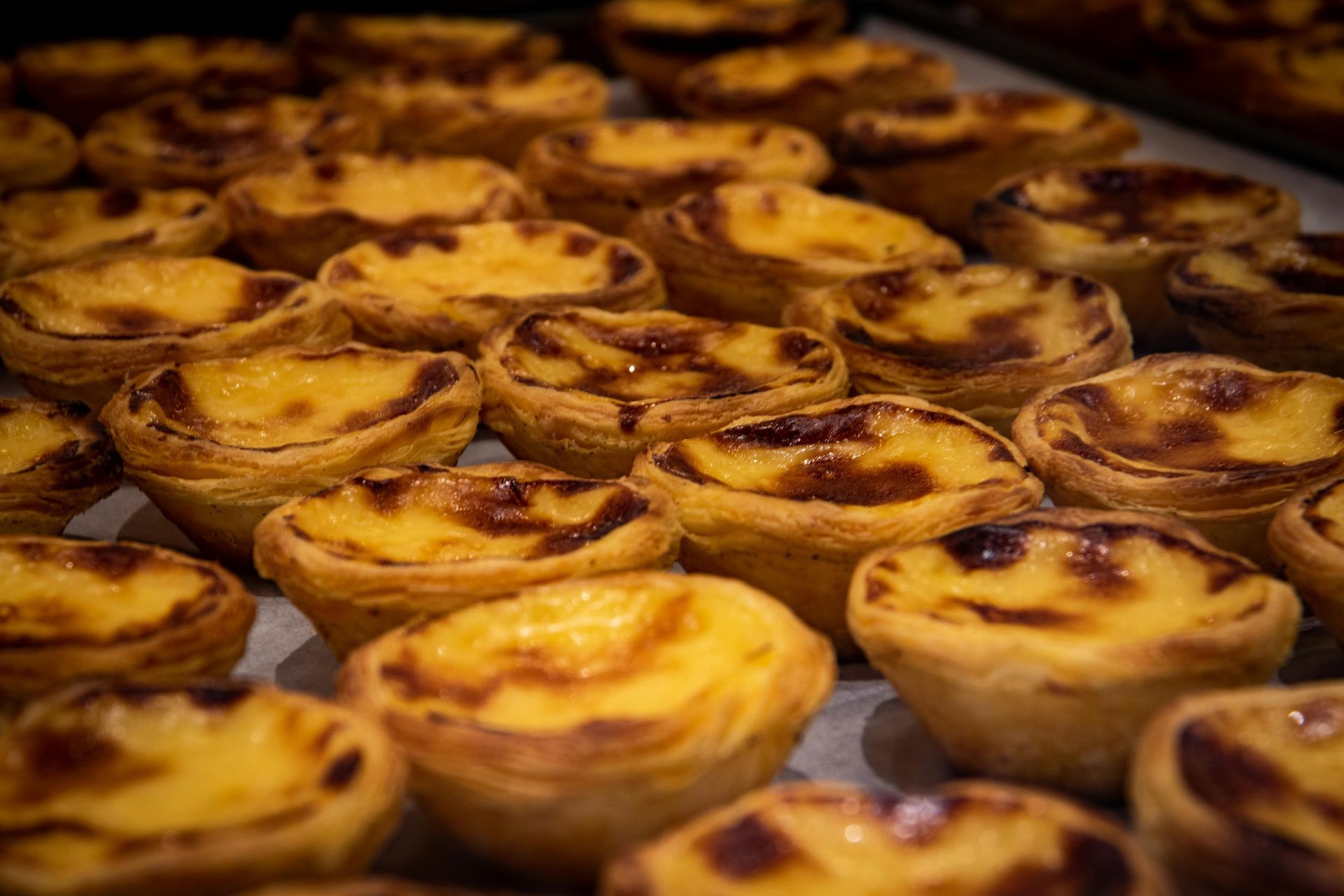 A bunch of Custard tarts known as Pasteis de Belem are sitting on a table.
