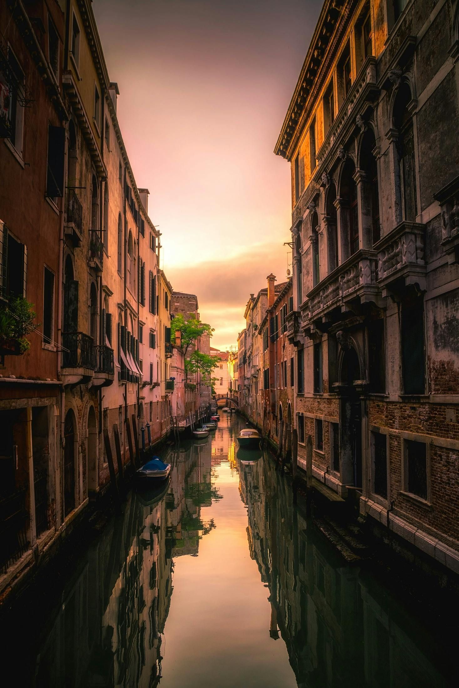 A narrow canal between two buildings in Venice at sunset.