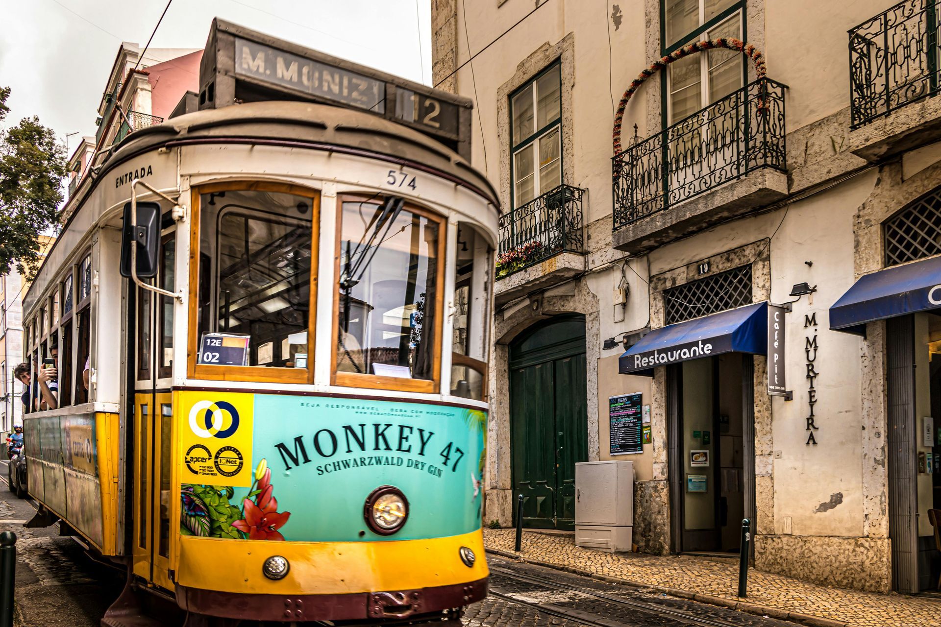 A trolley is going down a narrow street in the city of Lisbon.