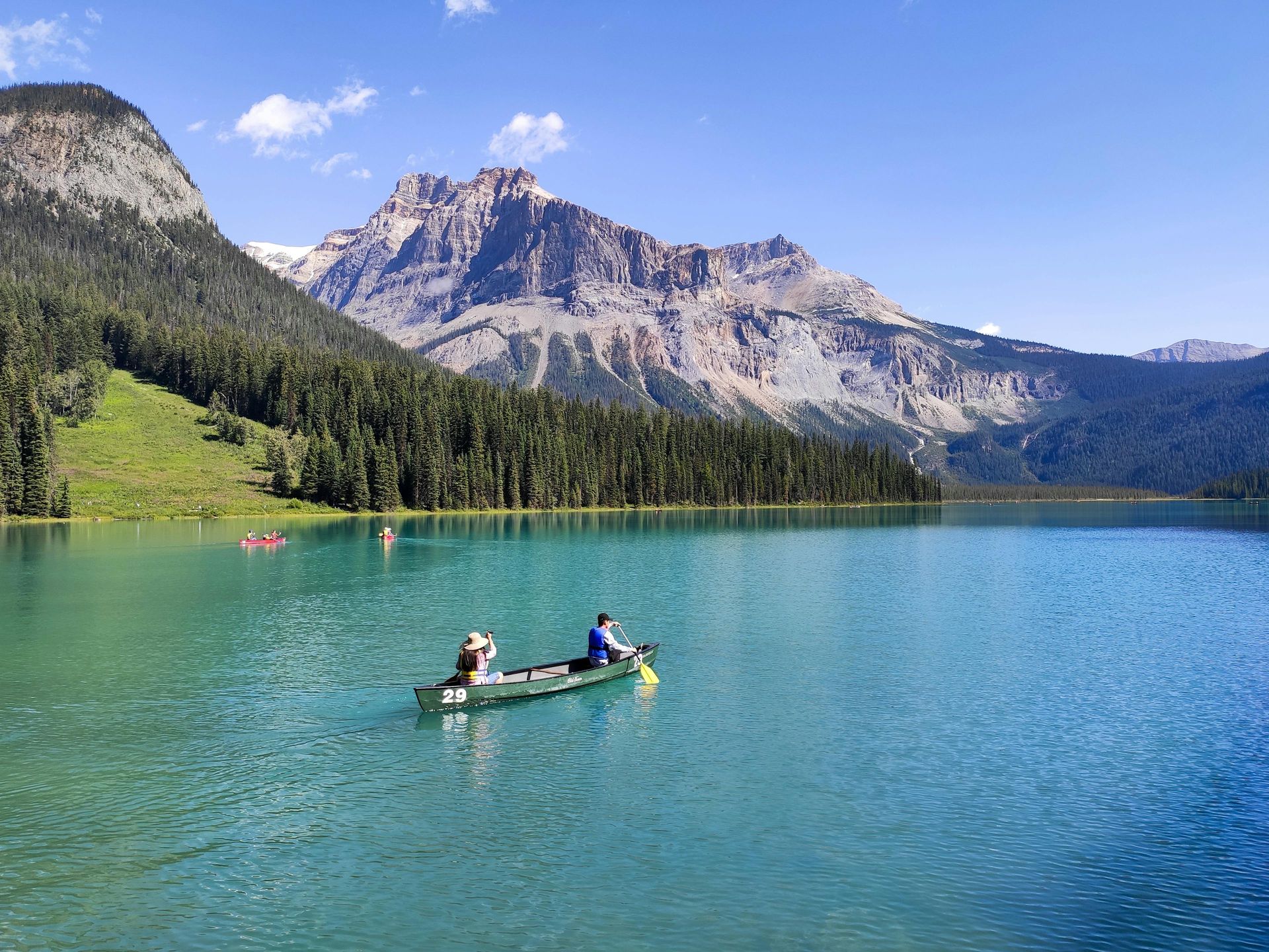 Two people are in a canoe on a lake with mountains in the background in Canada
