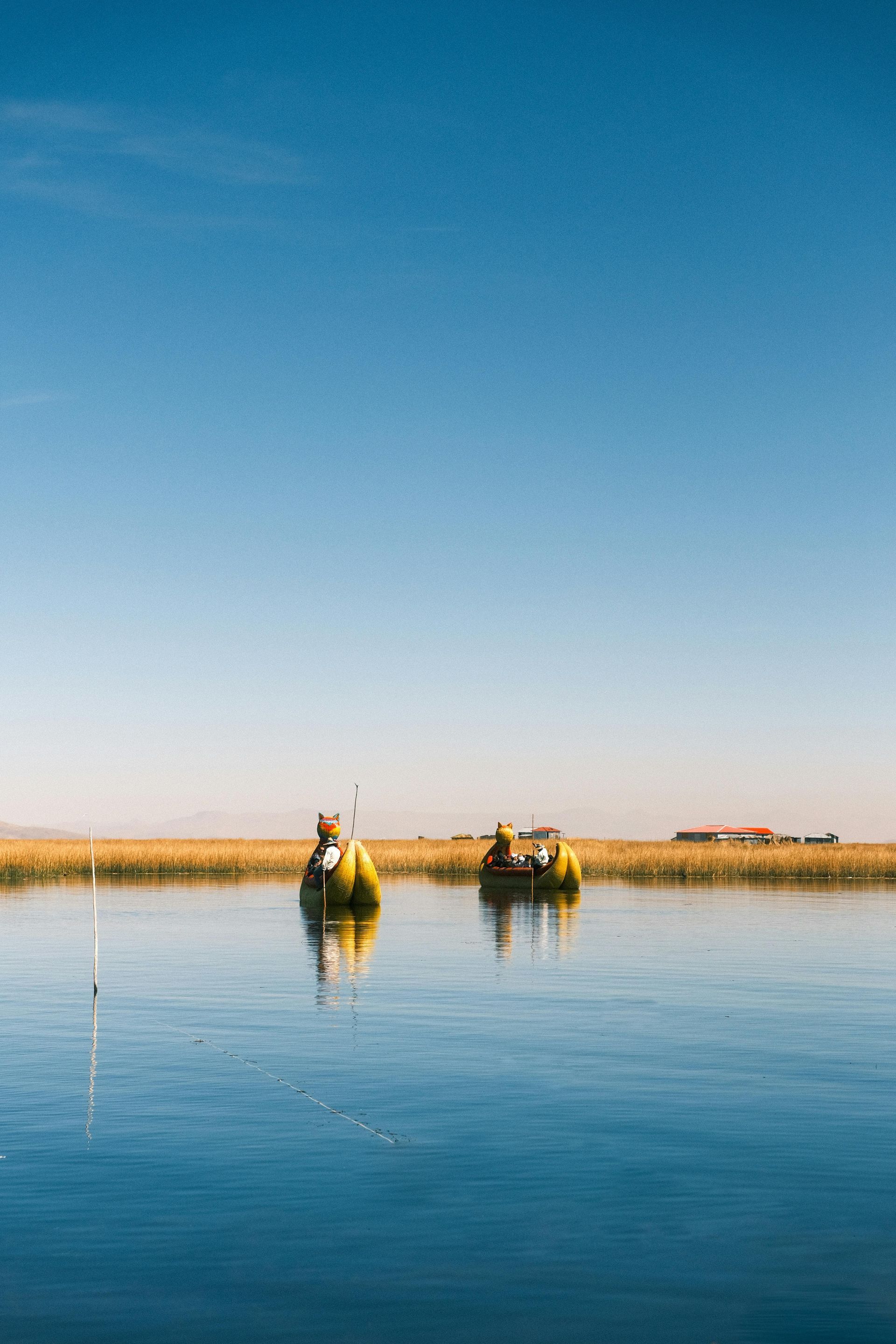 Two people are rowing boats on lake titicaca.