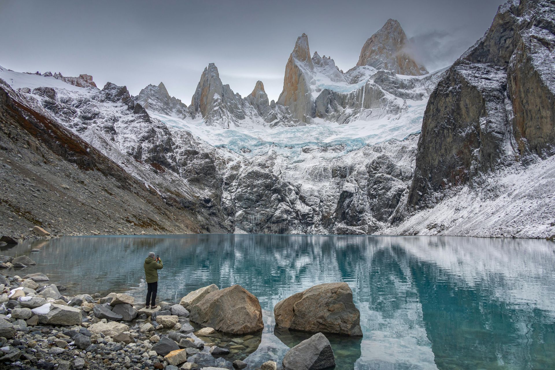 A person is standing next to a lake in the Patagonia mountains.