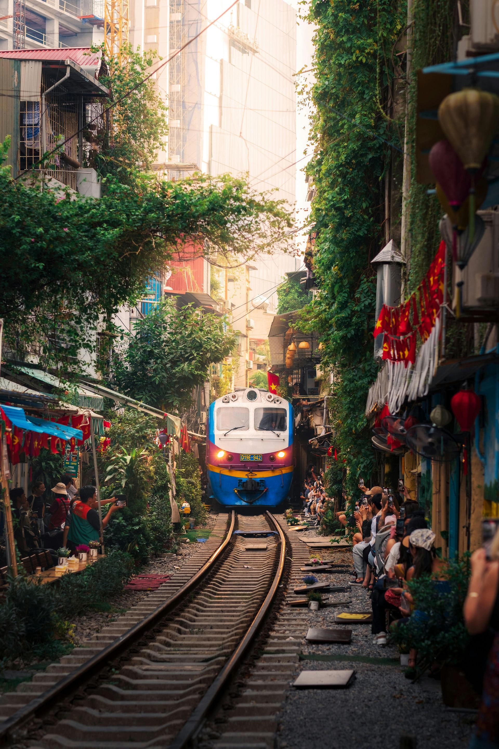 The Reunification Express train is going down train tracks in a narrow alleyway.
