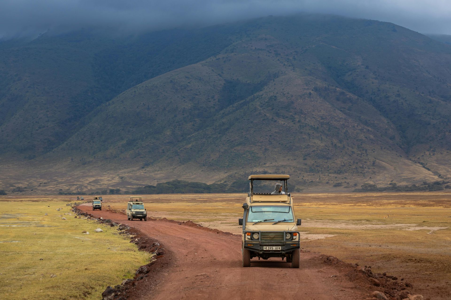 A group of jeep 's are driving down a dirt road in Ngorongoro Crater