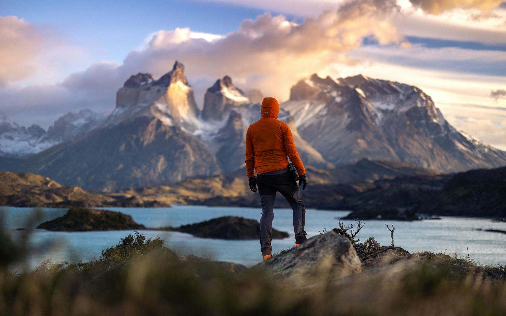 A man is standing on top of a mountain overlooking a lake In Chile