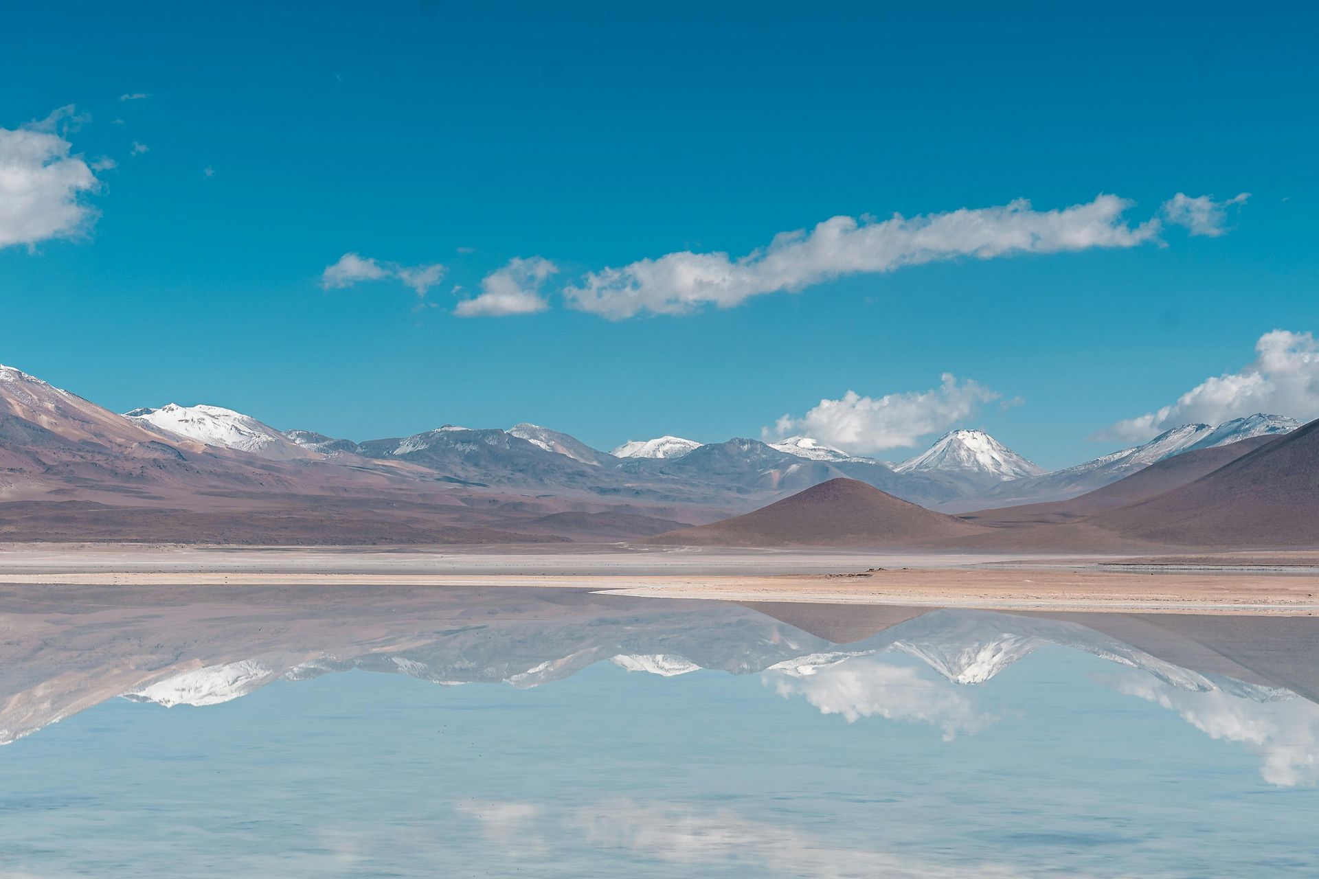 A lake with mountains in the background and mountains reflected in the water.