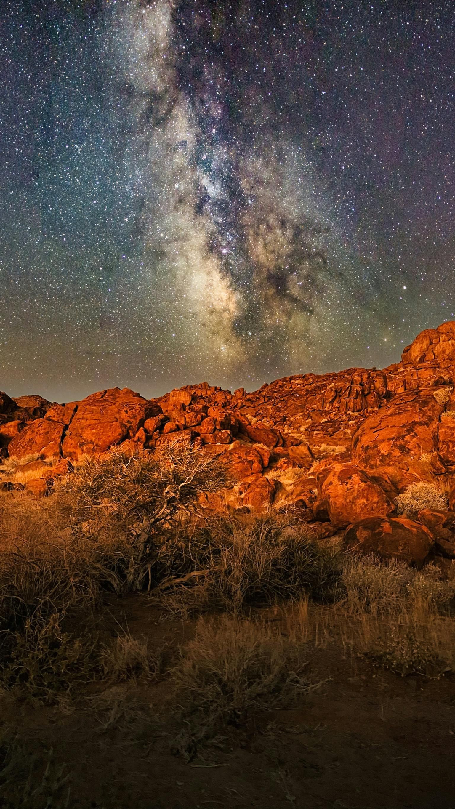 The milky way is visible over a rocky landscape at night in the Namib Desert
