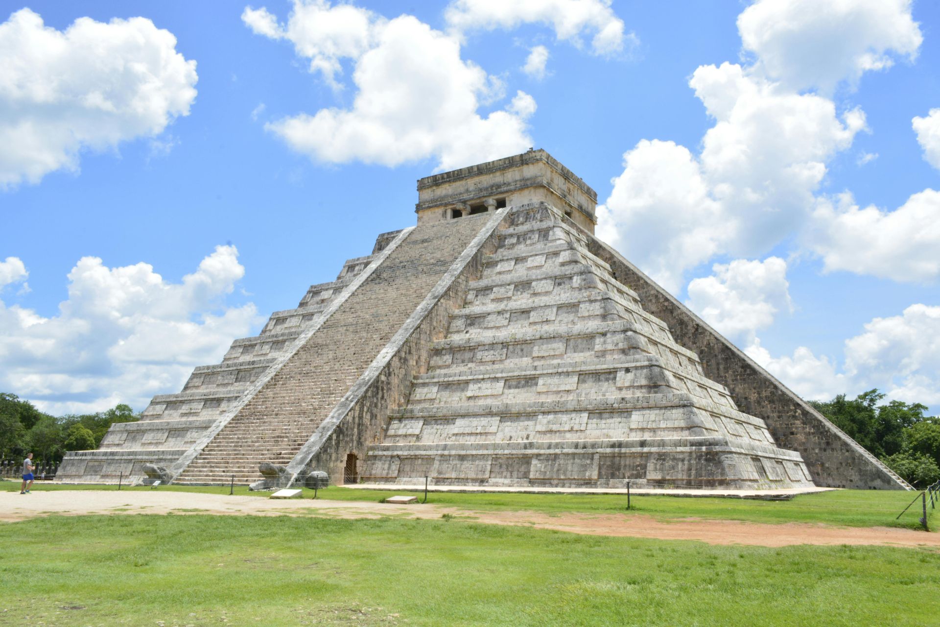 A large stone pyramid is sitting in the middle of a grassy field.
