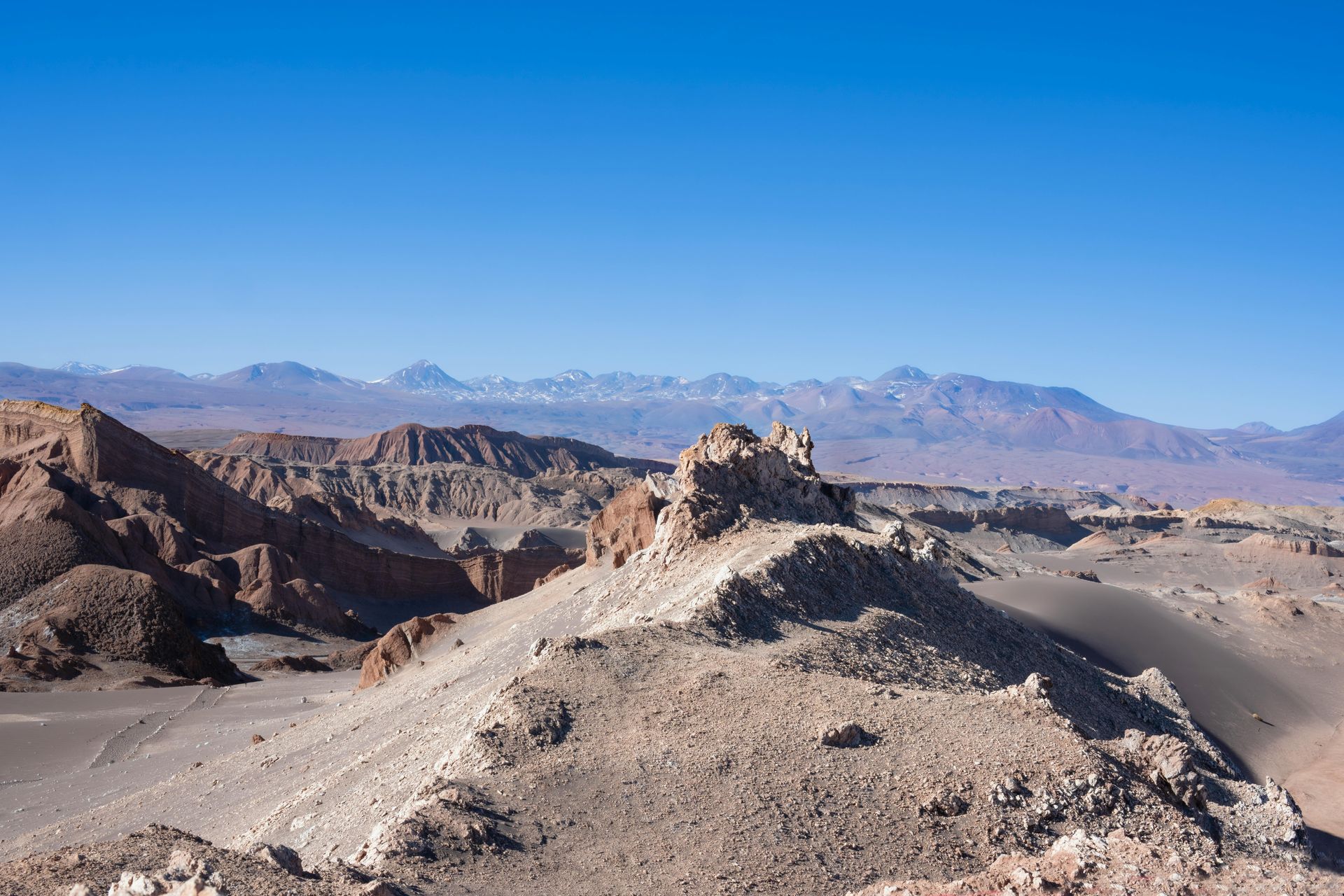 A desert landscape with mountains in the background and a blue sky in the Atacama Desert