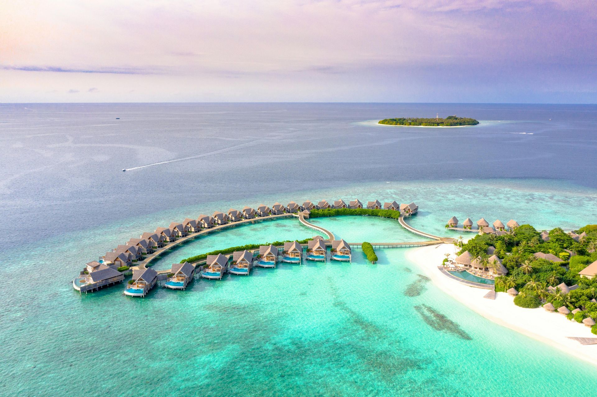 An aerial view of a resort in the middle of the ocean with over the water bungalows in Maldives