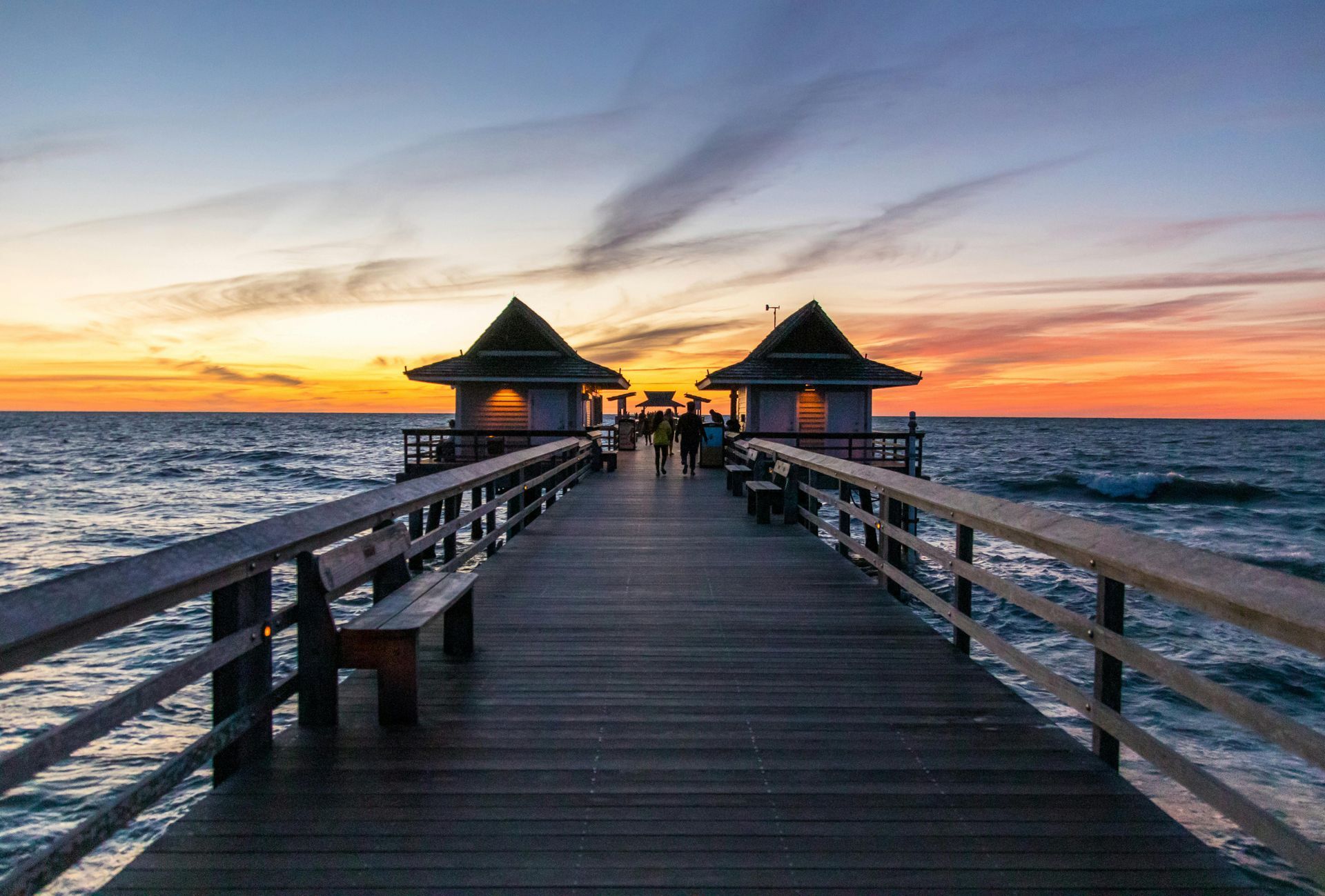 A wooden pier leading into the ocean at sunset in Florida