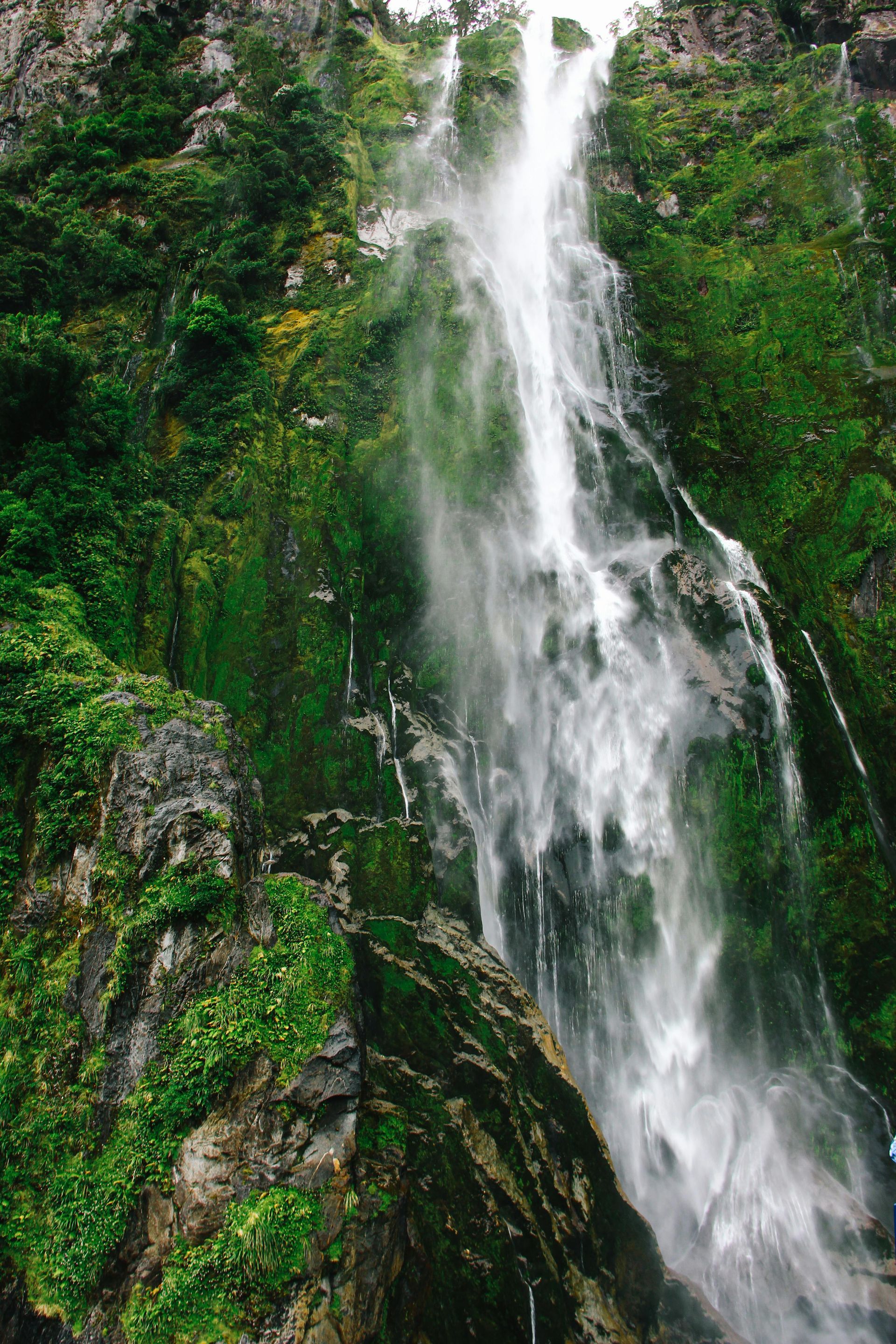 A waterfall is surrounded by trees and rocks in the middle of a forest.