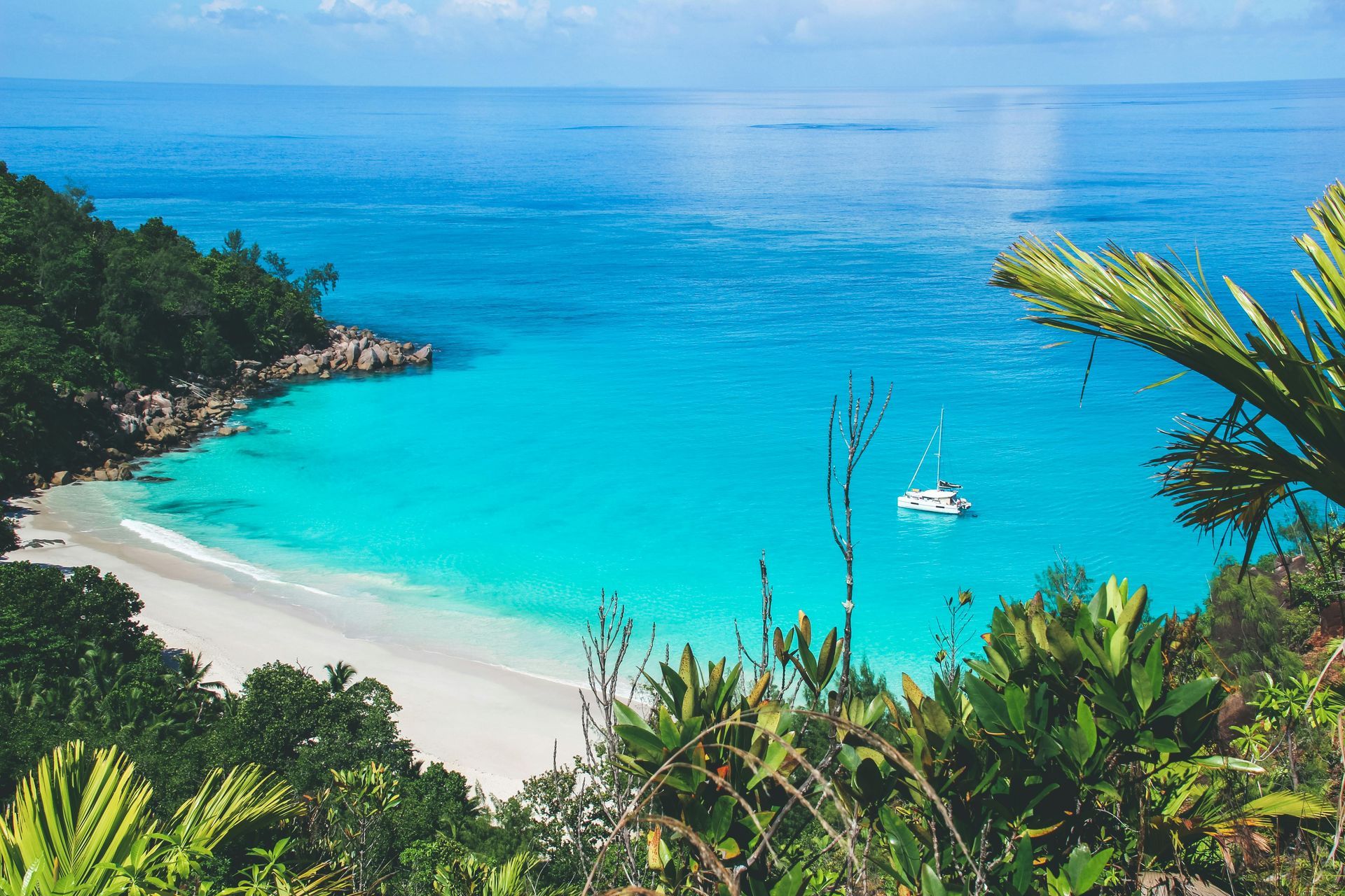 A boat is floating on the water near a beach surrounded by trees in Seychelles