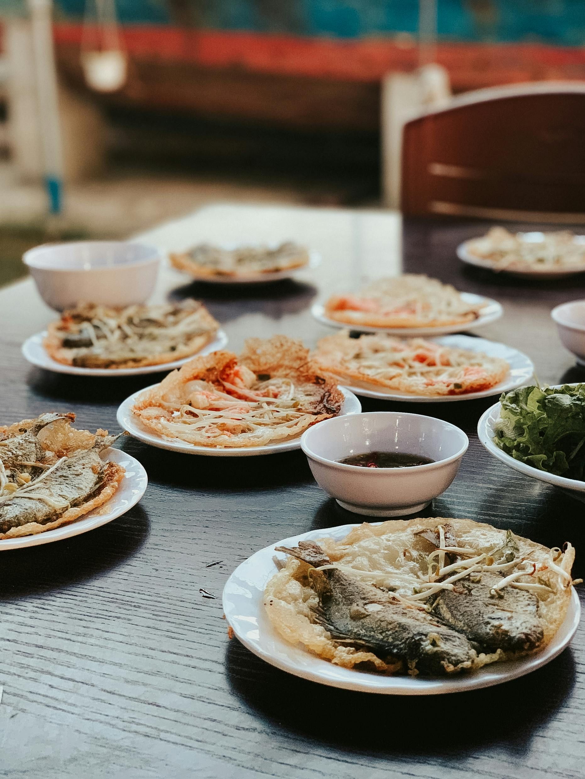 A table topped with plates of food and bowls of dipping sauce in Vietnam