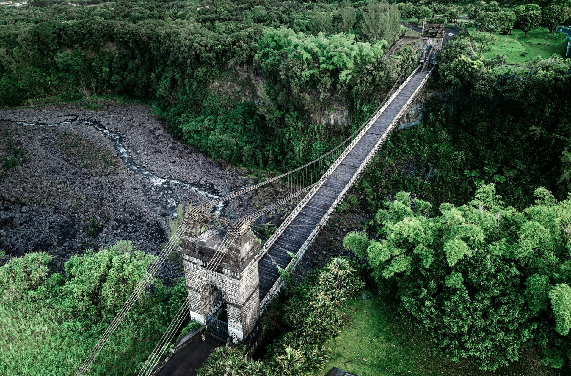 An aerial view of a bridge over a river in the middle of a forest.
