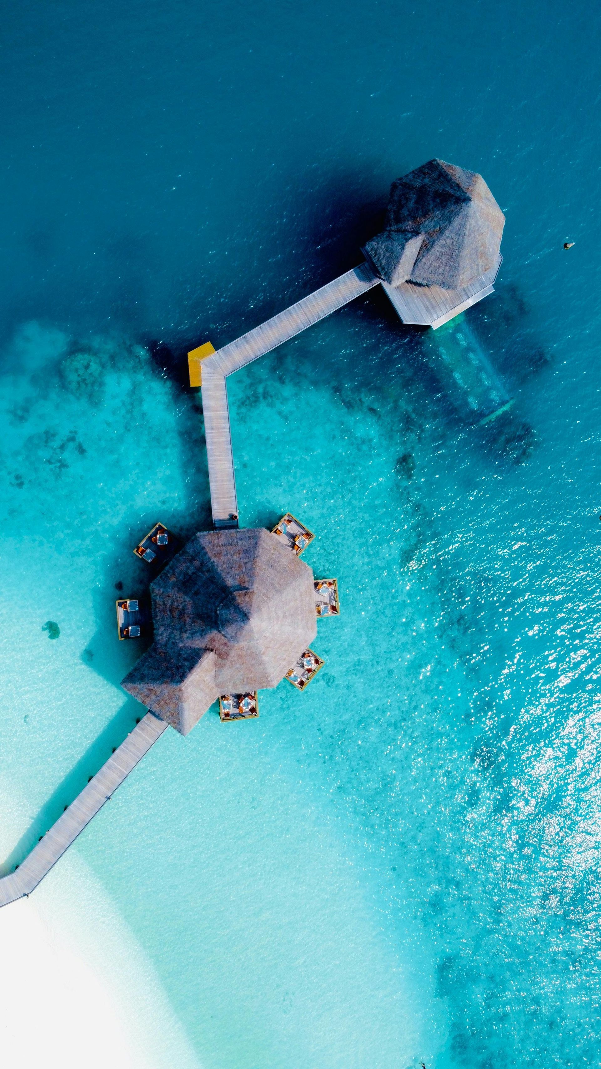 An aerial view of a small water bungalow in the middle of the ocean.