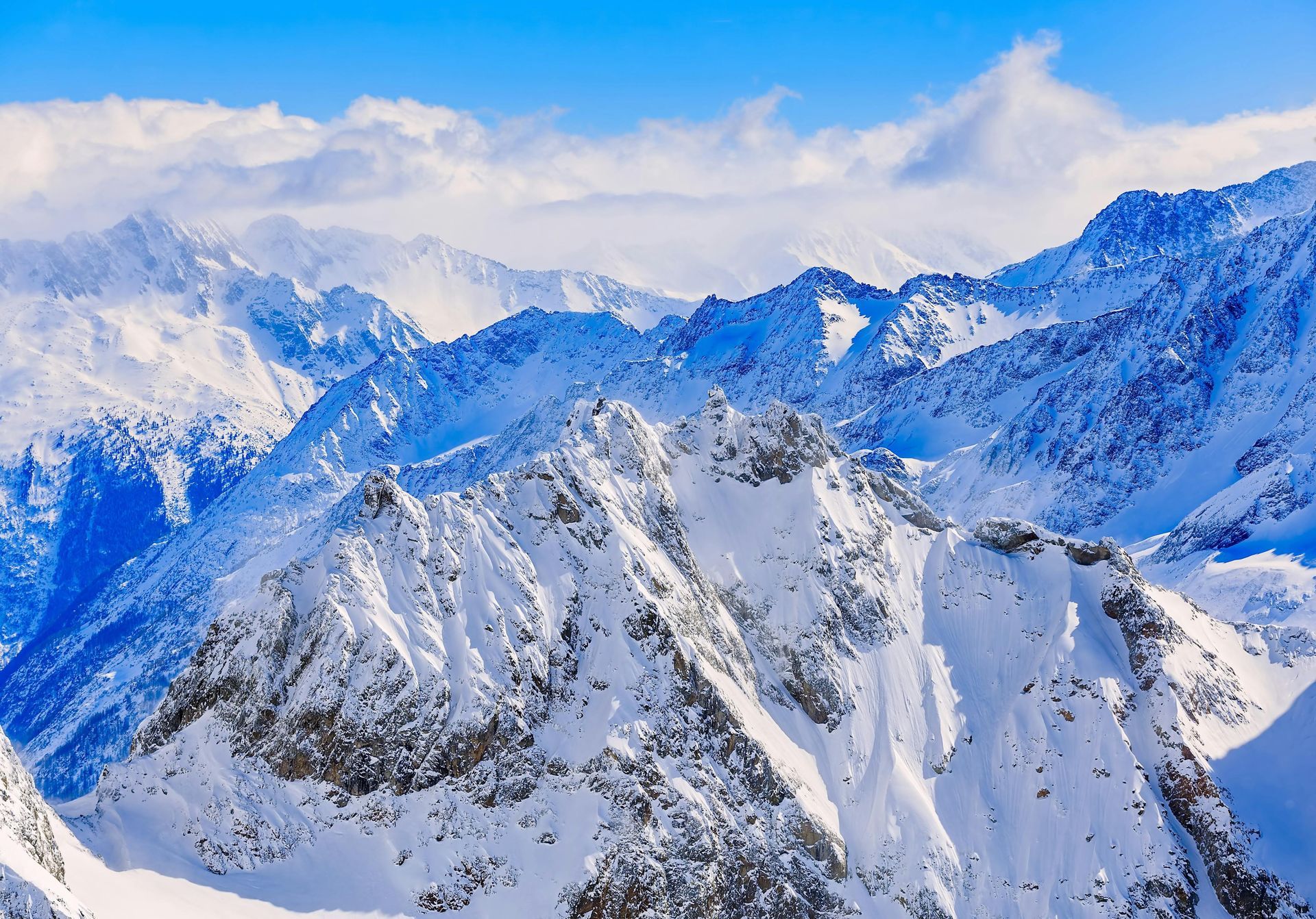 A snowy mountain range in the French Alps with a blue sky in the background