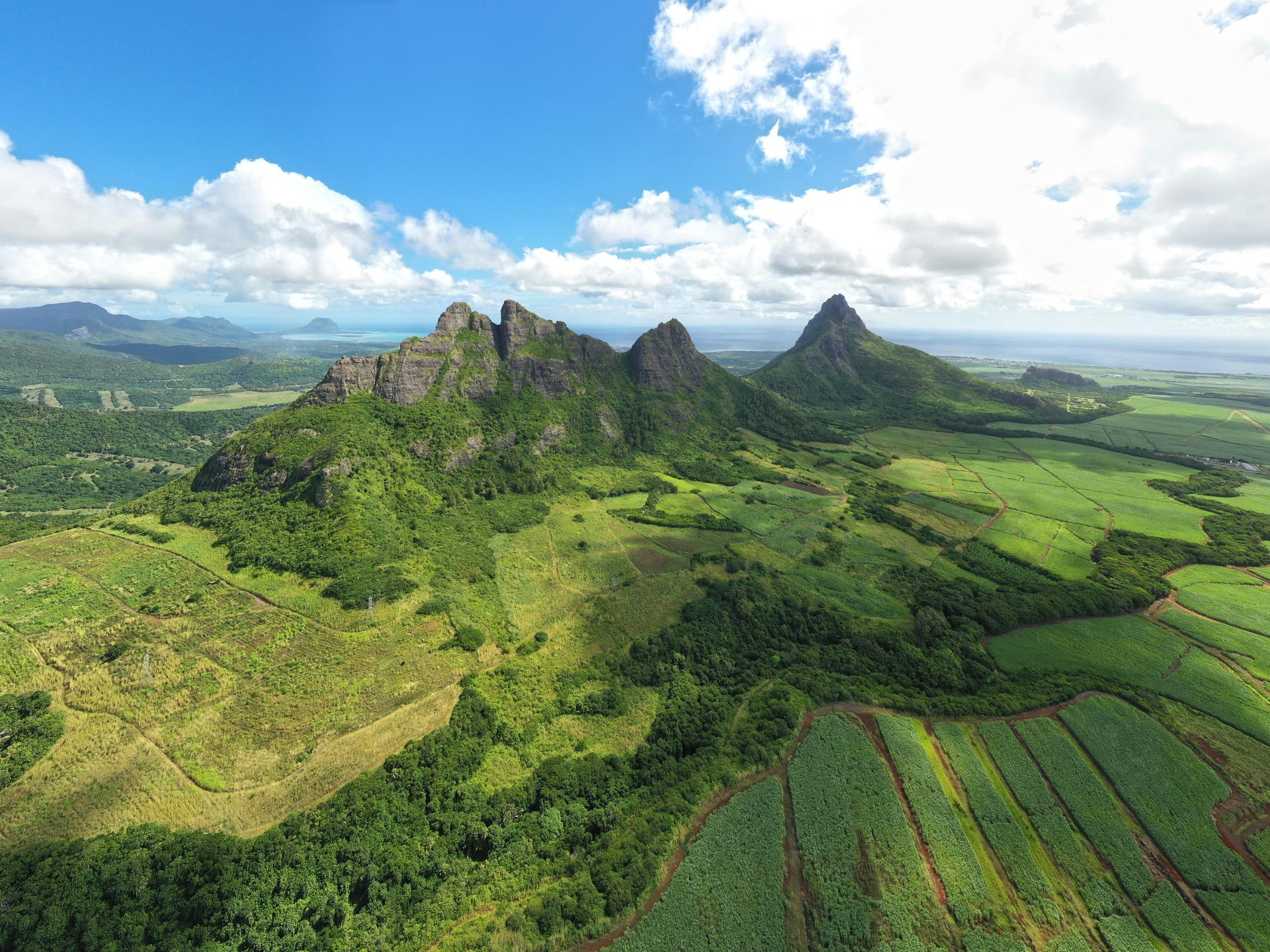 An aerial view of a mountain range surrounded by lush green fields in Mauritius