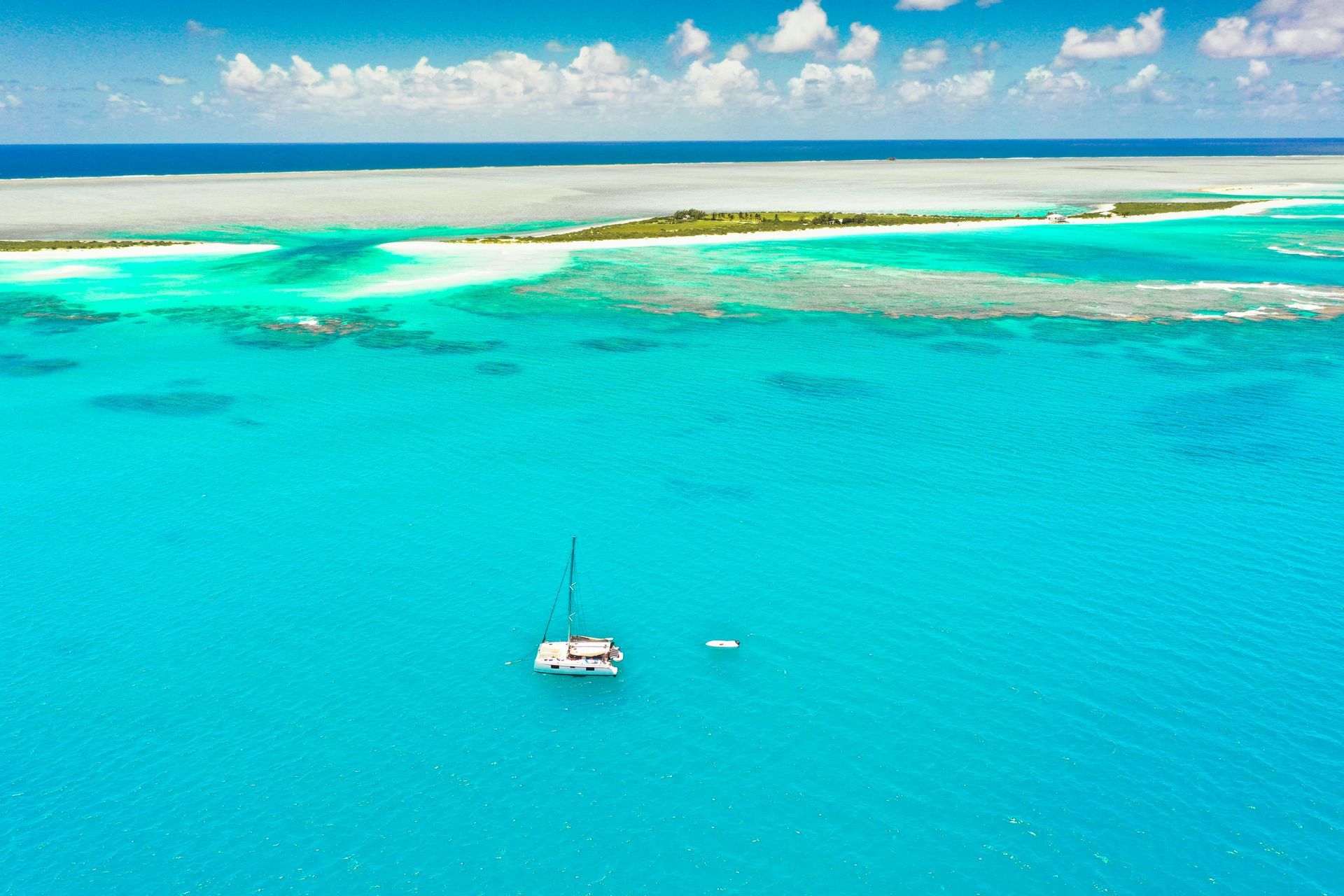 An aerial view of a sailboat in the middle of the ocean.