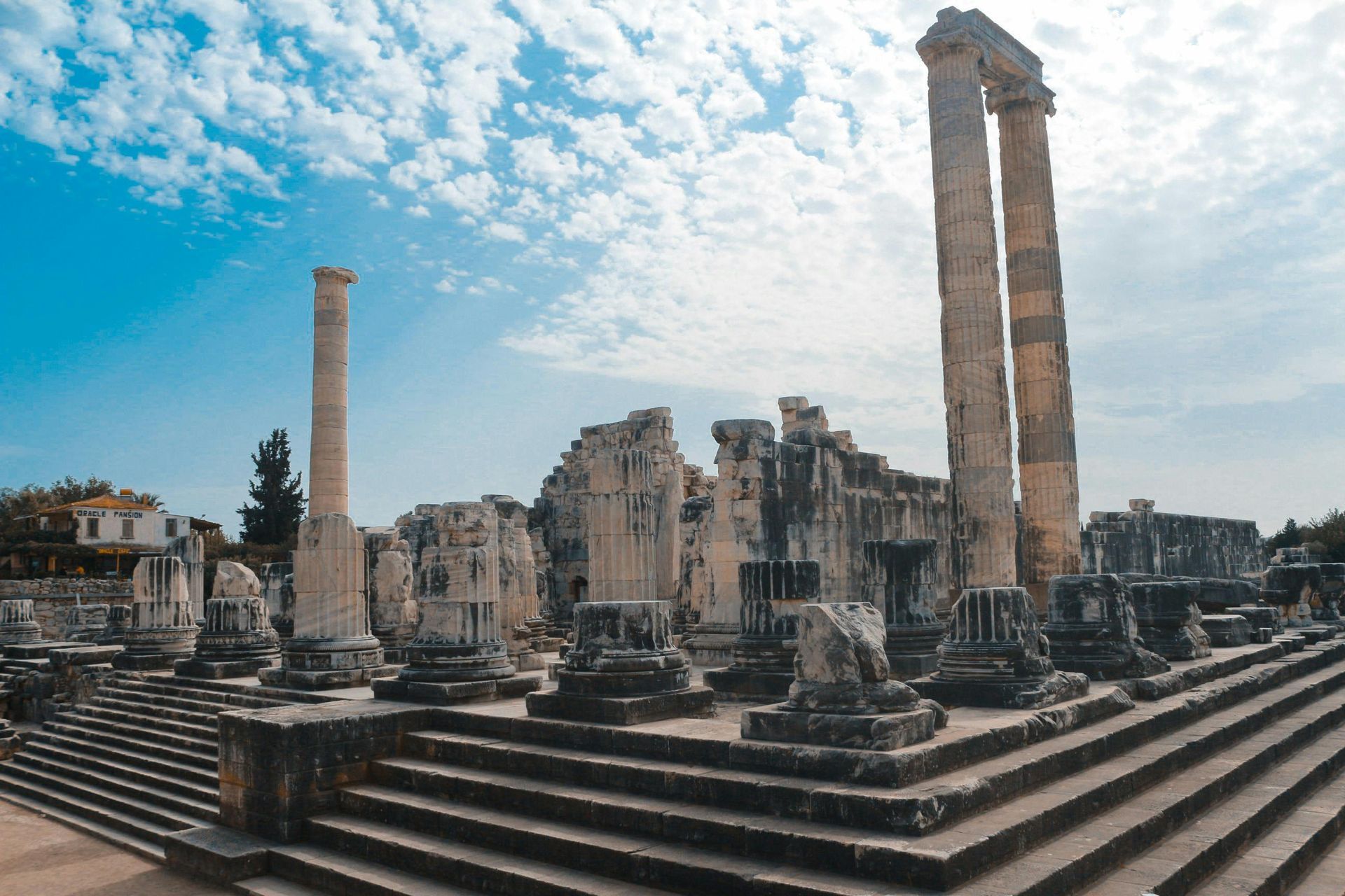 A group of ancient ruins with columns and stairs in front of a blue sky.