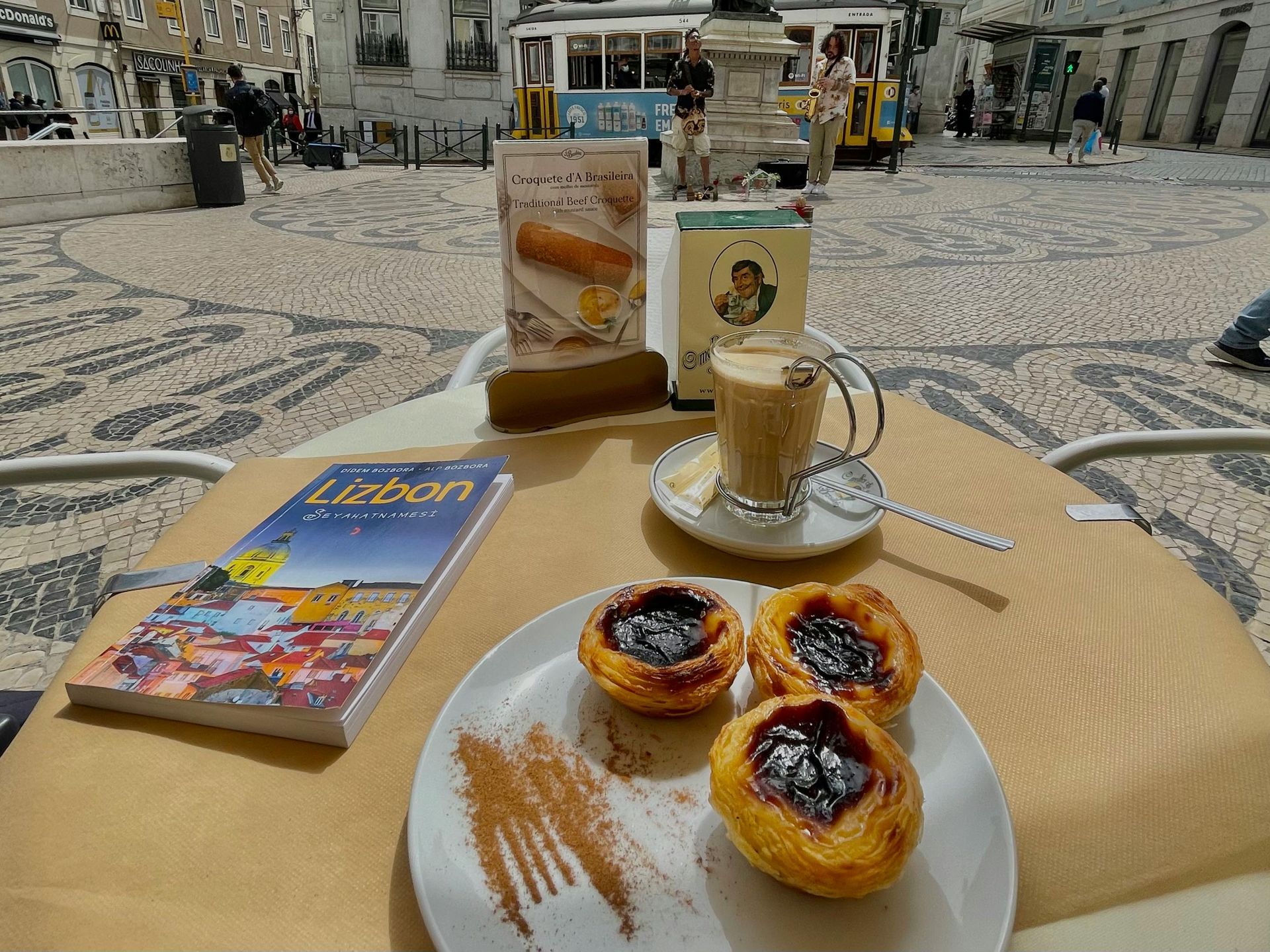 A table with a plate of pastries and a cup of coffee.