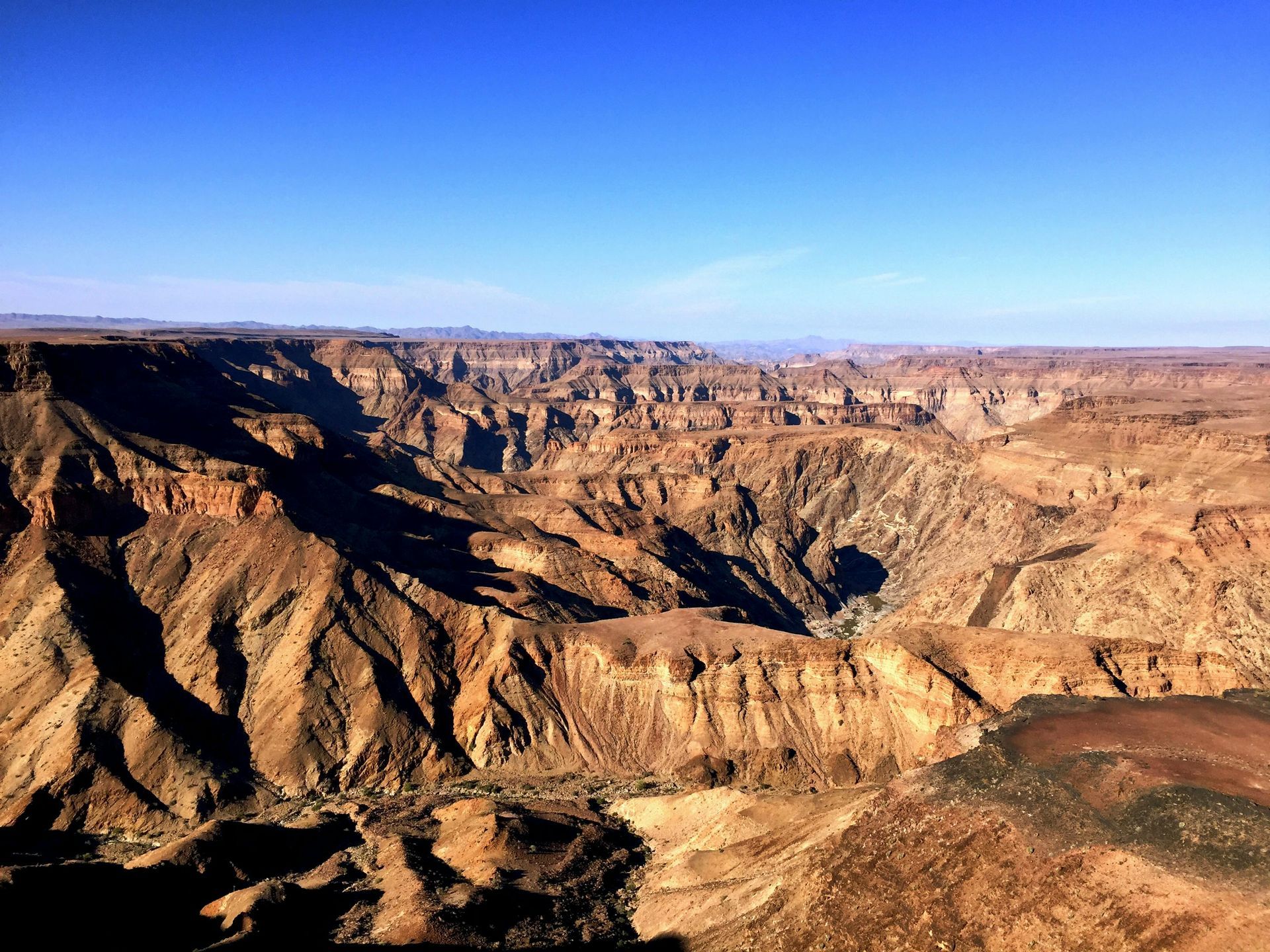 An aerial view of Fish River canyon with a blue sky in the background.