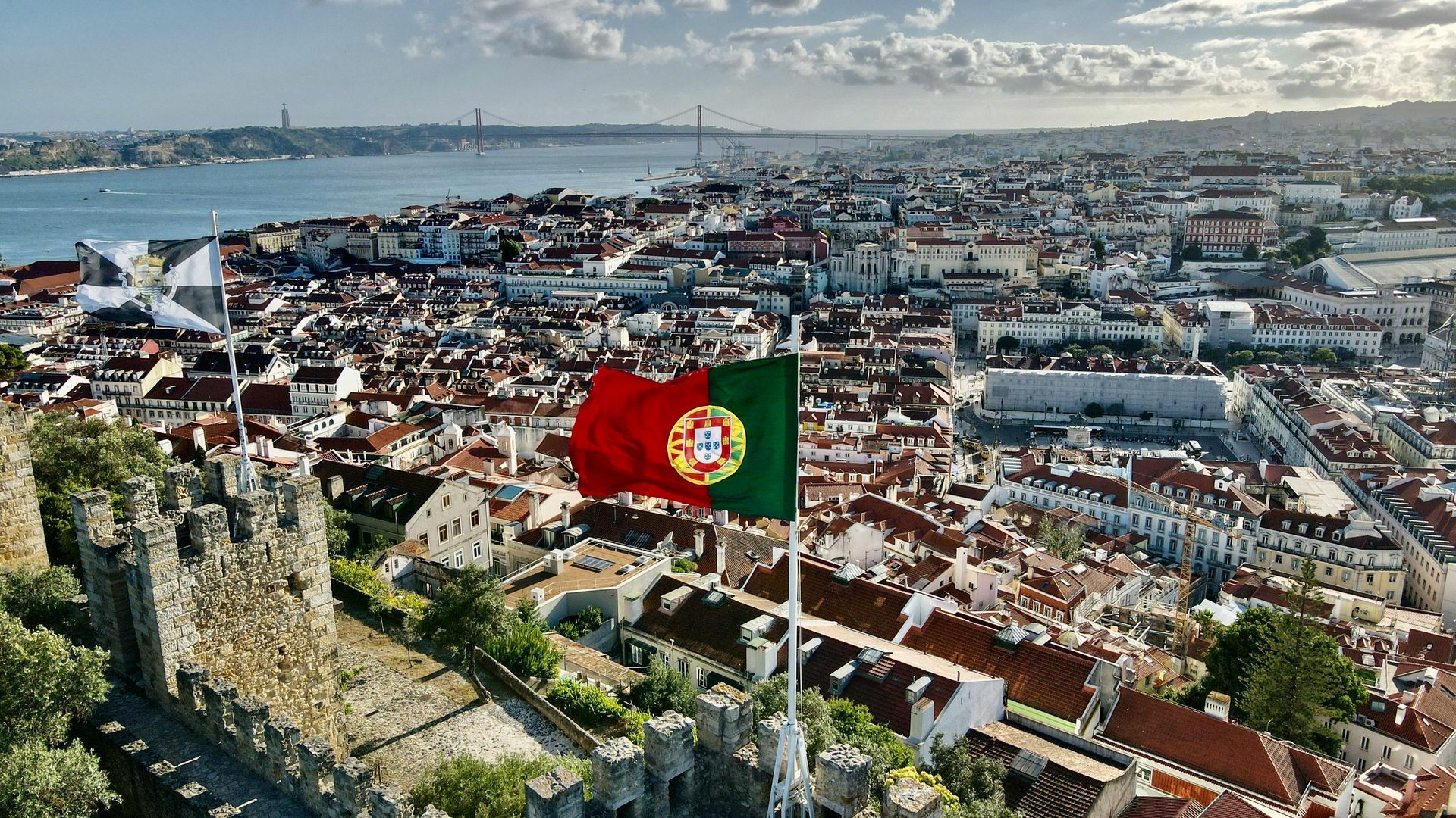 An aerial view of the city Lisbon with a Portugal flag flying in the foreground.